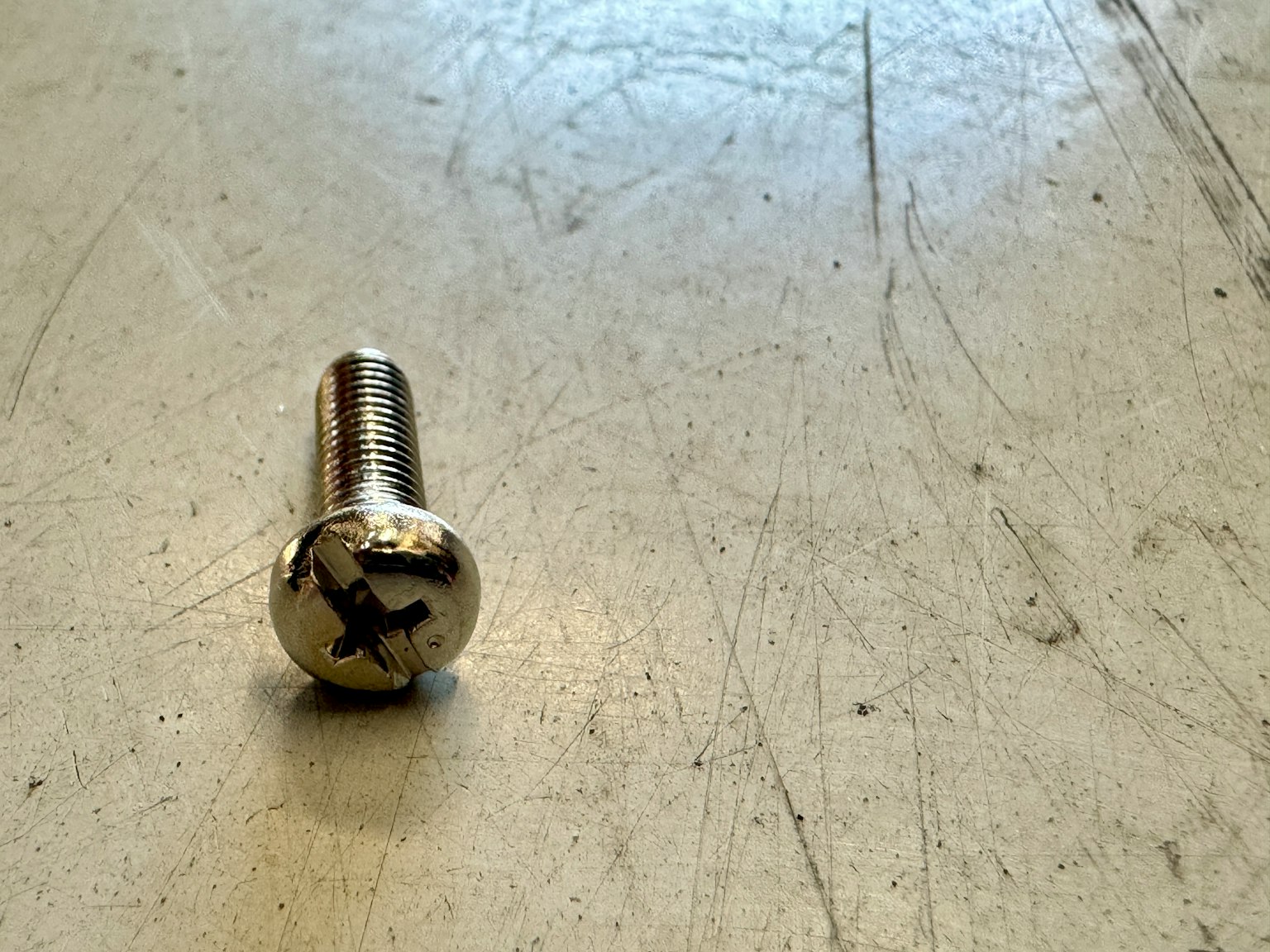 Un tornillo de metal colocado sobre una superficie de mesa