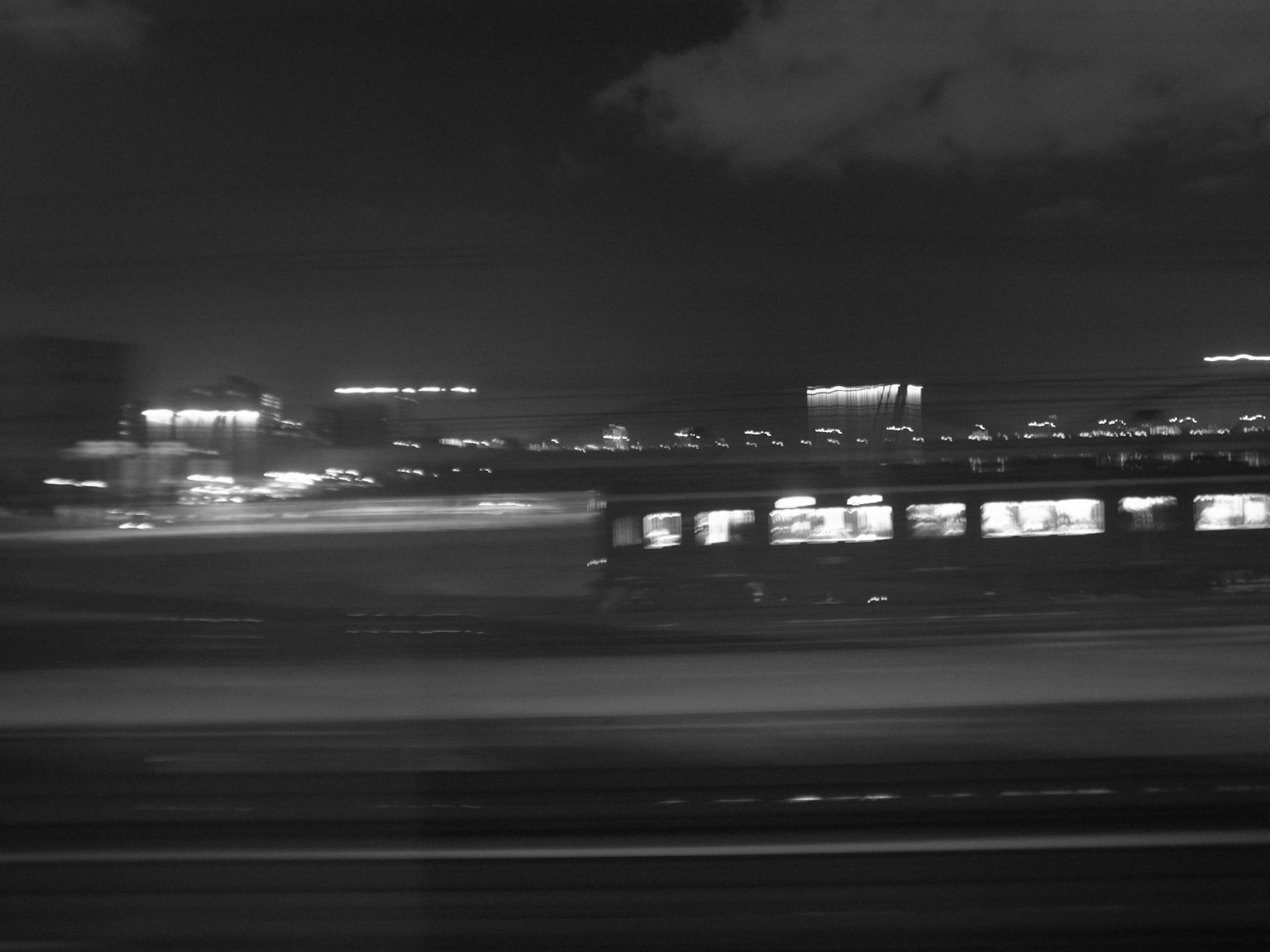 Un treno in movimento di notte con luci sfocate della città sullo sfondo
