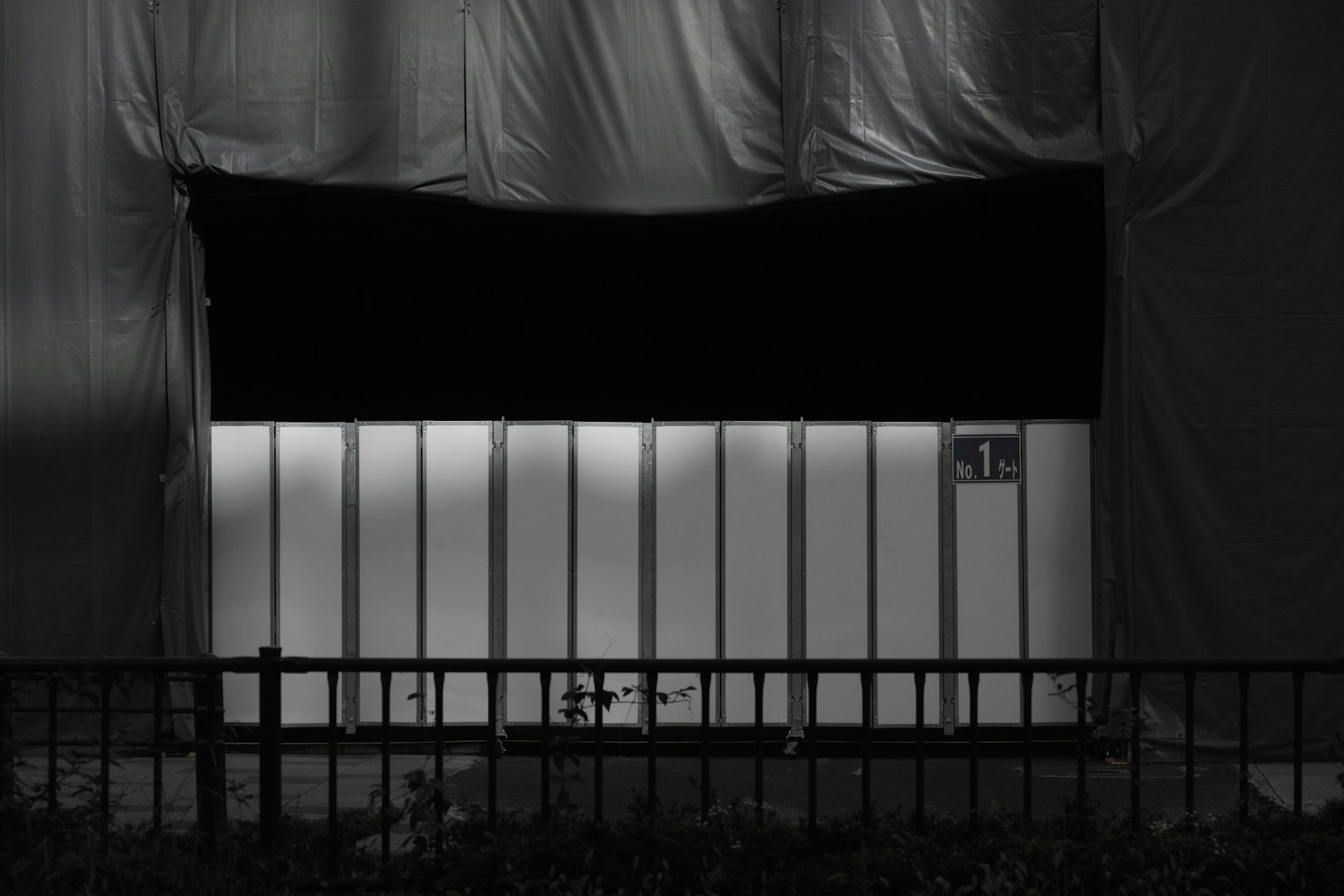 ein Abschnitt eines Gebäudes mit weißen Glaswänden und einem schwarzen Vorhang vor einem dunklen Hintergrund