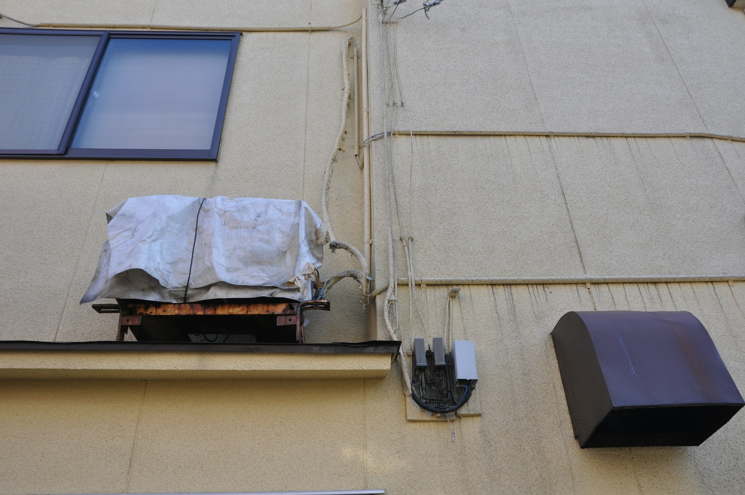 Scene of an air conditioning unit and electrical box mounted on a building's exterior wall