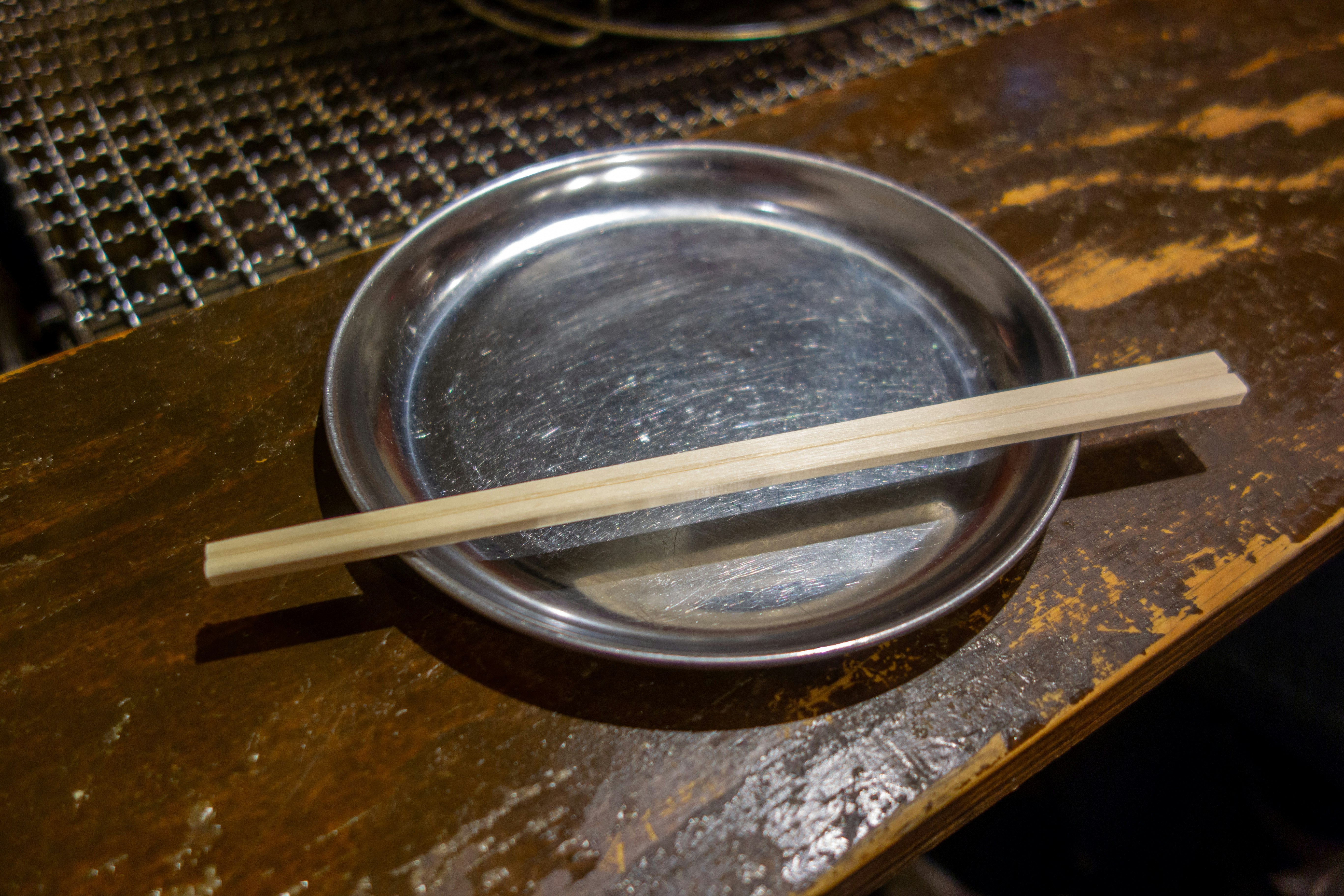 Table de repas japonaise avec des baguettes à côté d’un plat métallique