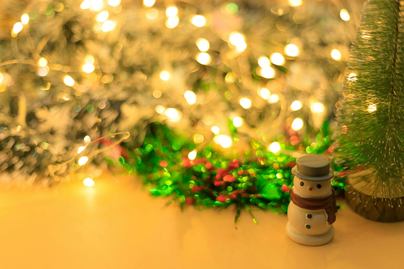 Muñeco de nieve frente a un árbol de Navidad con luces brillantes