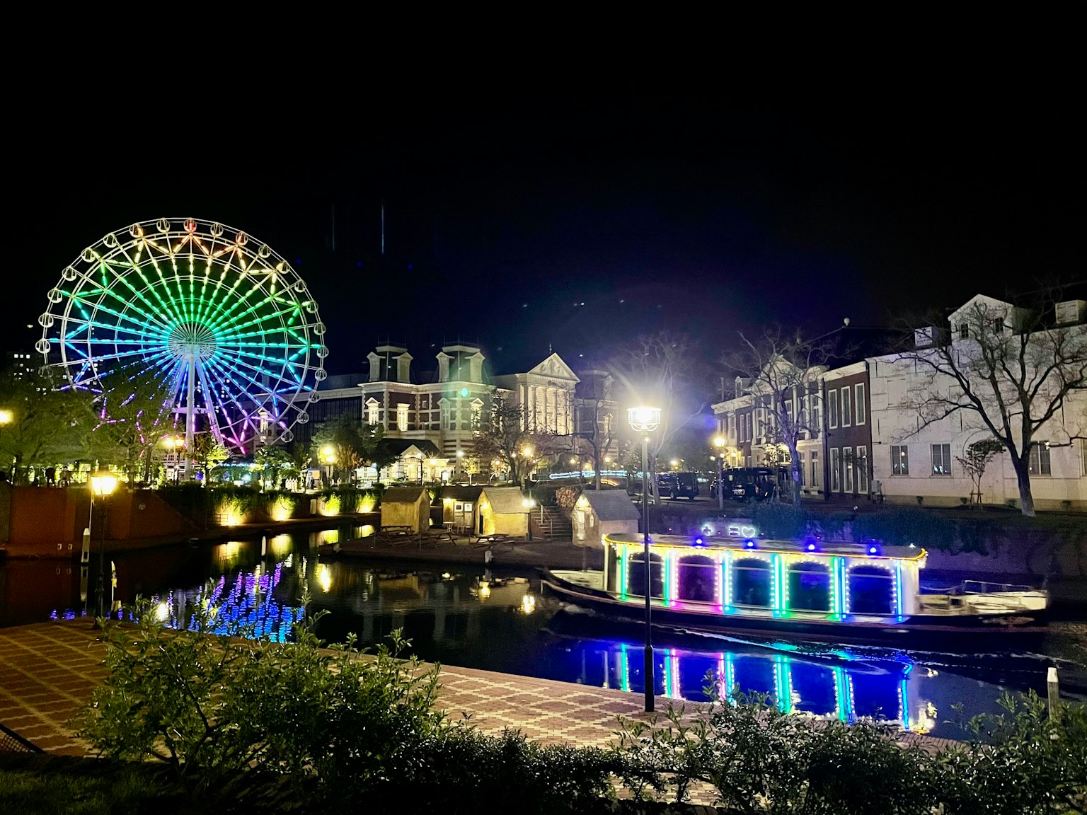 夜景，色彩繽紛的摩天輪和河上的照明船
