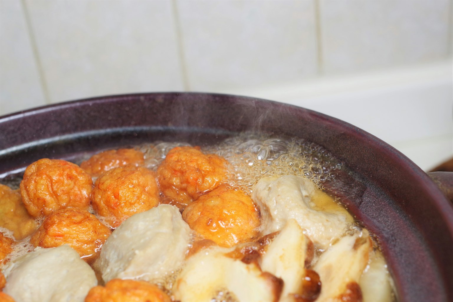 Steaming pot with orange and white dumplings boiling