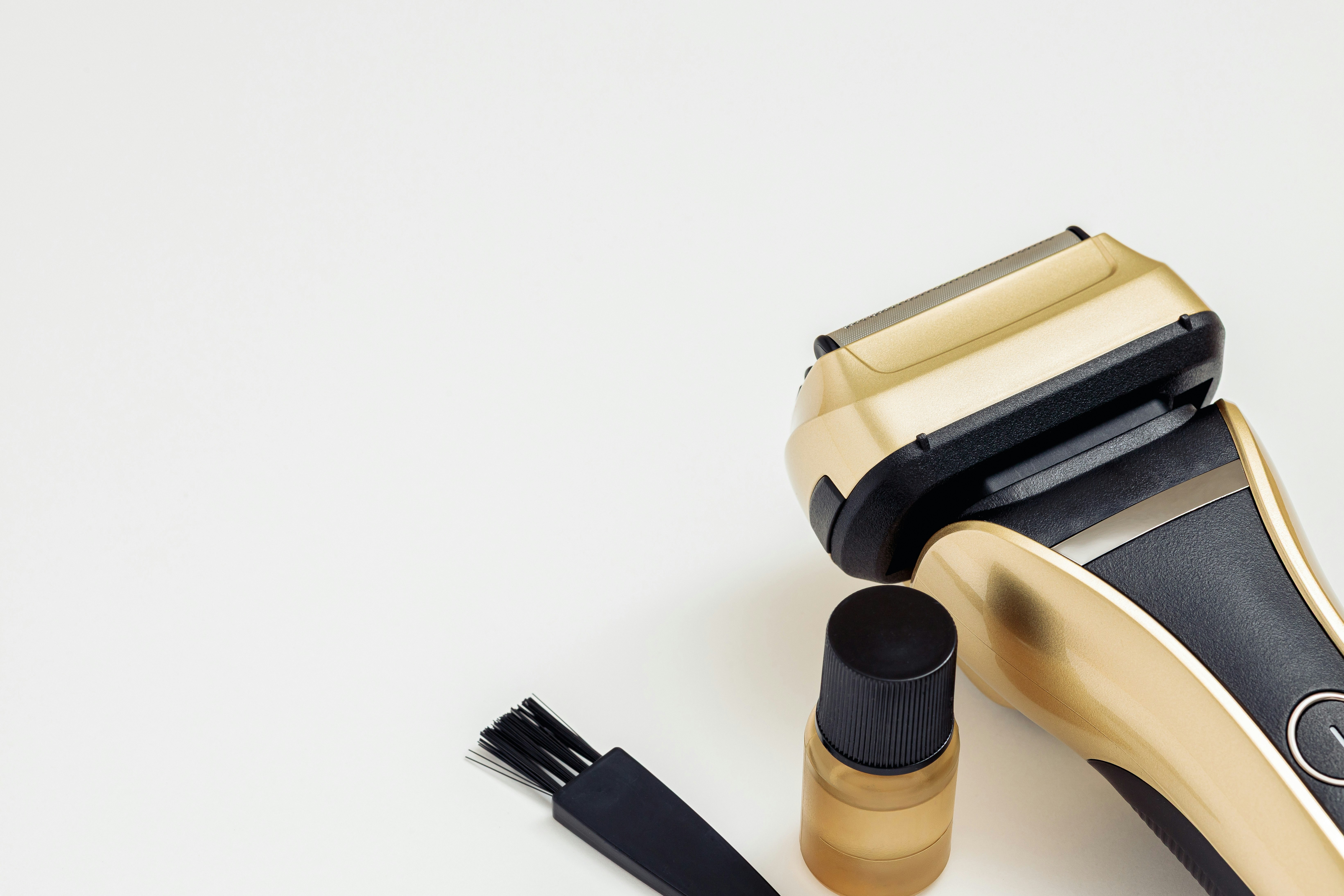 rasoir électrique beige avec spray coiffant et peigne sur fond clair