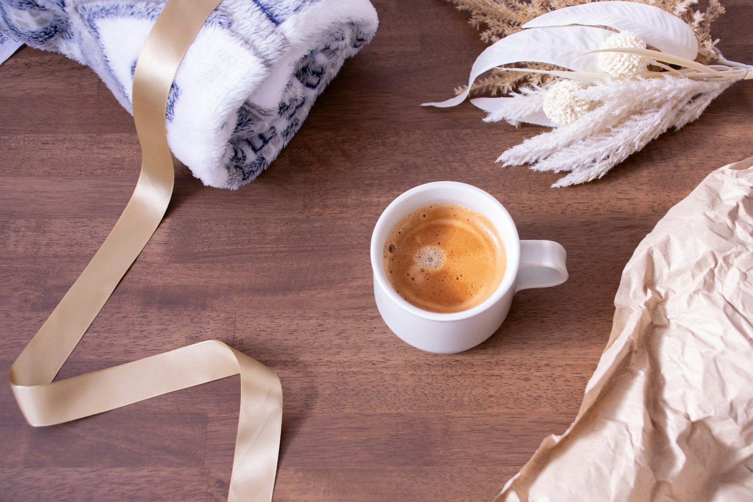 Warm coffee cup with a blanket and dried flowers on a wooden table