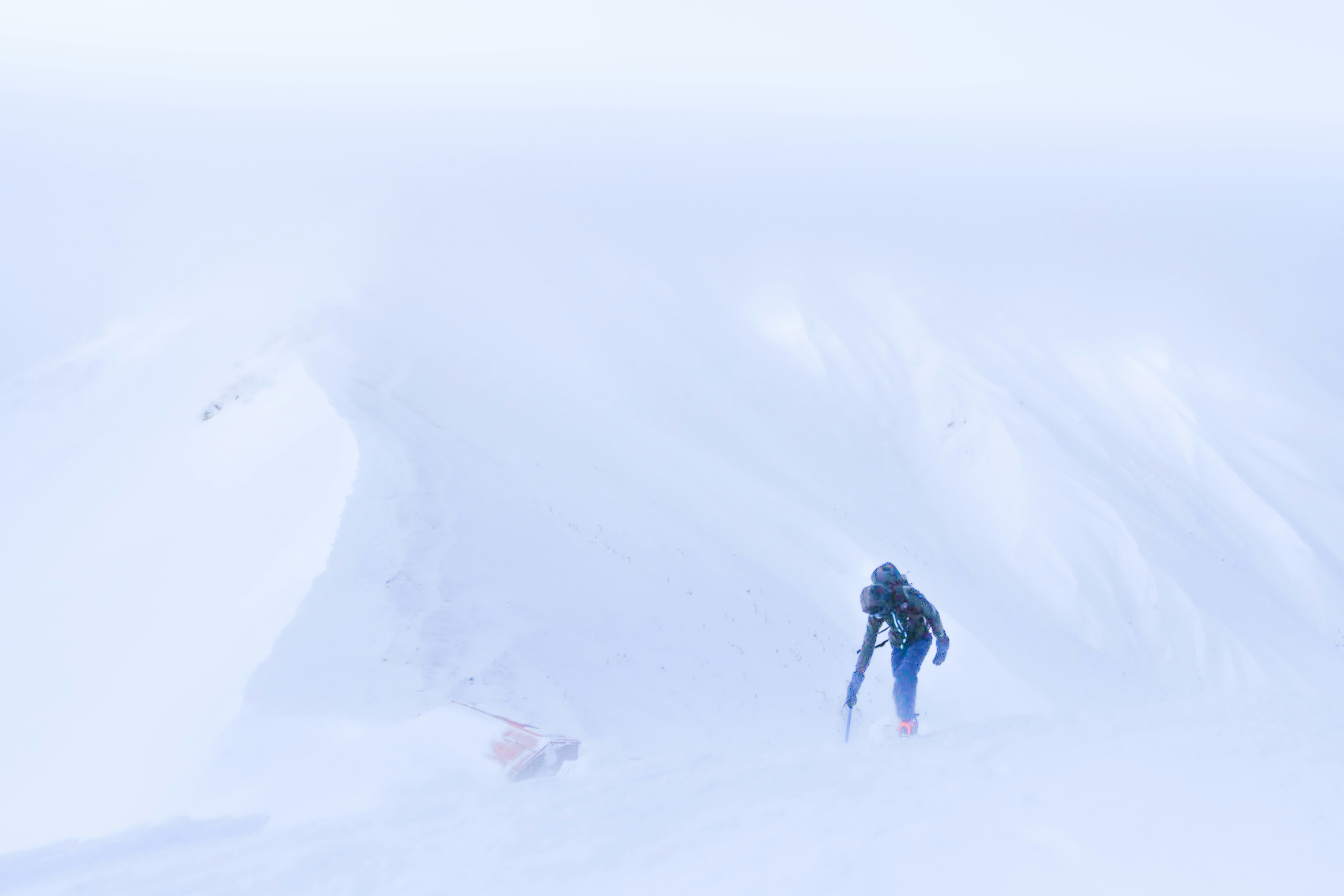 吹雪の雪山で歩く登山者のシルエット