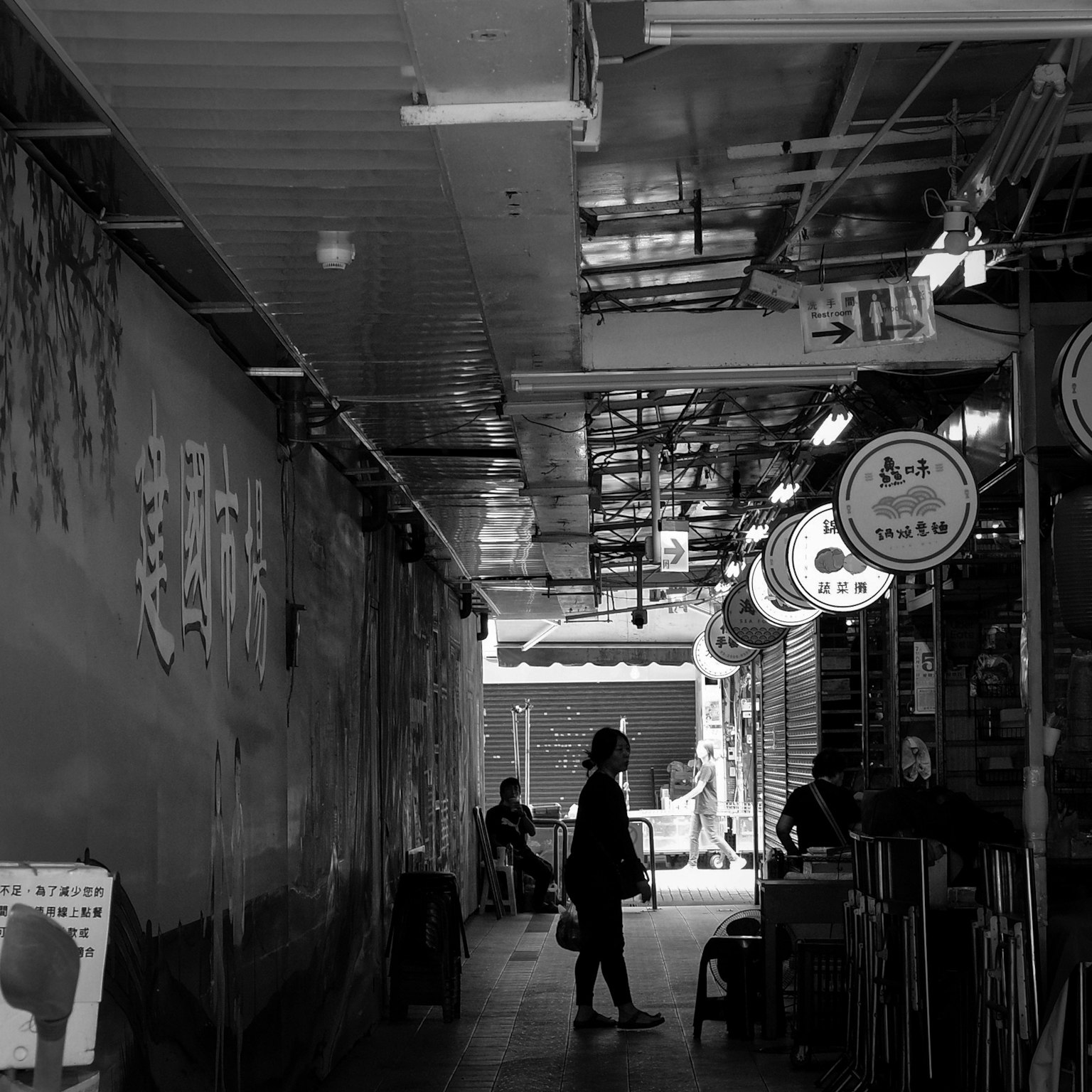 Silhouette di una persona in piedi in un'area commerciale in bianco e nero