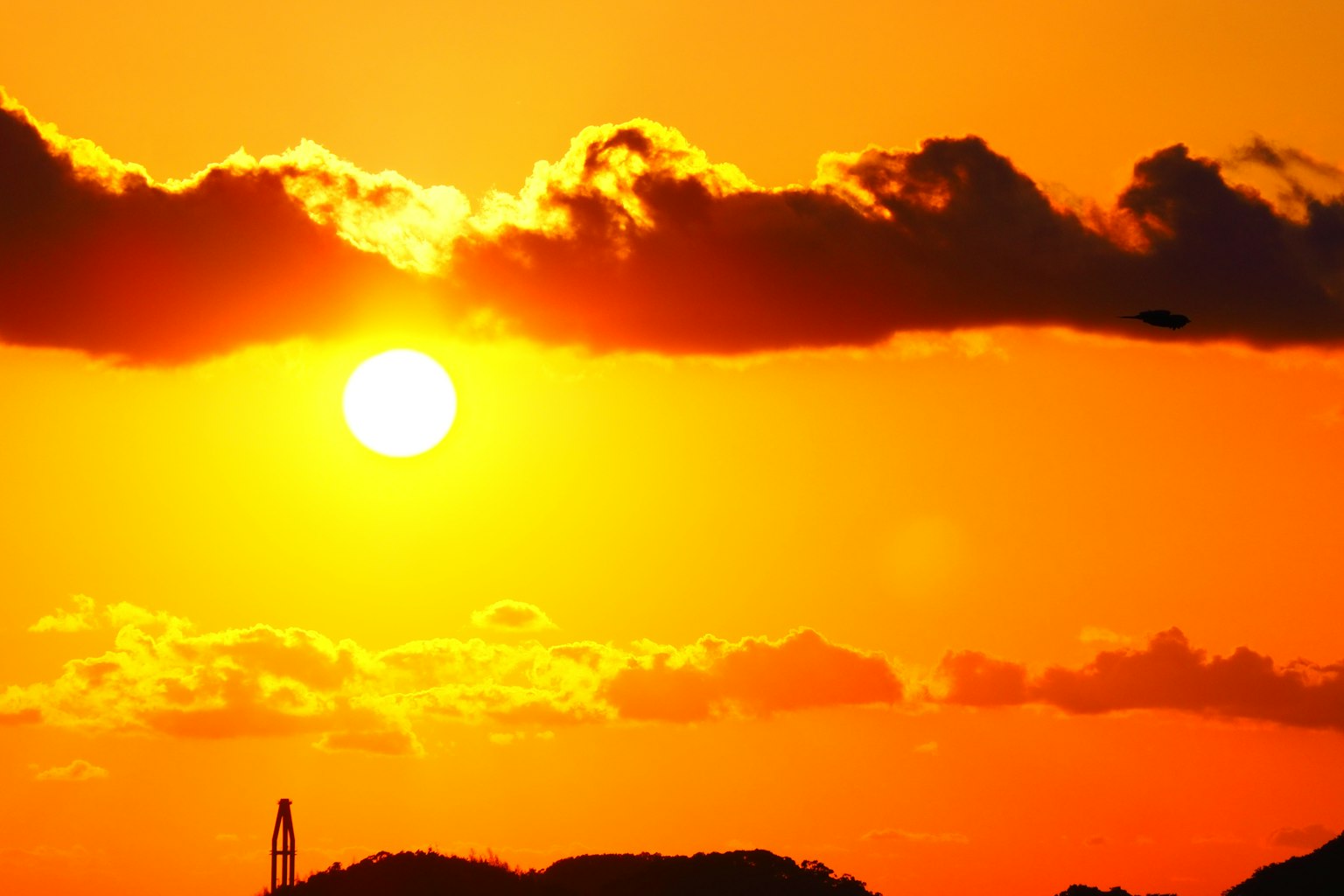 Sonnenuntergang mit Wolken und Bergen im Hintergrund lebendiger orangefarbener Himmel