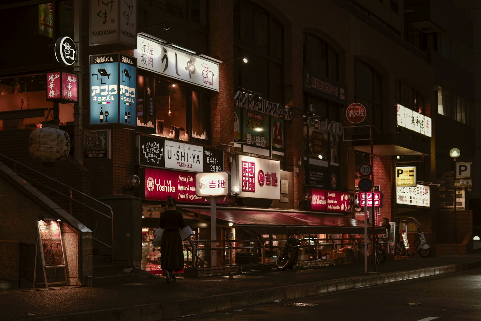 Escena nocturna de restaurantes con letreros iluminados en un entorno urbano