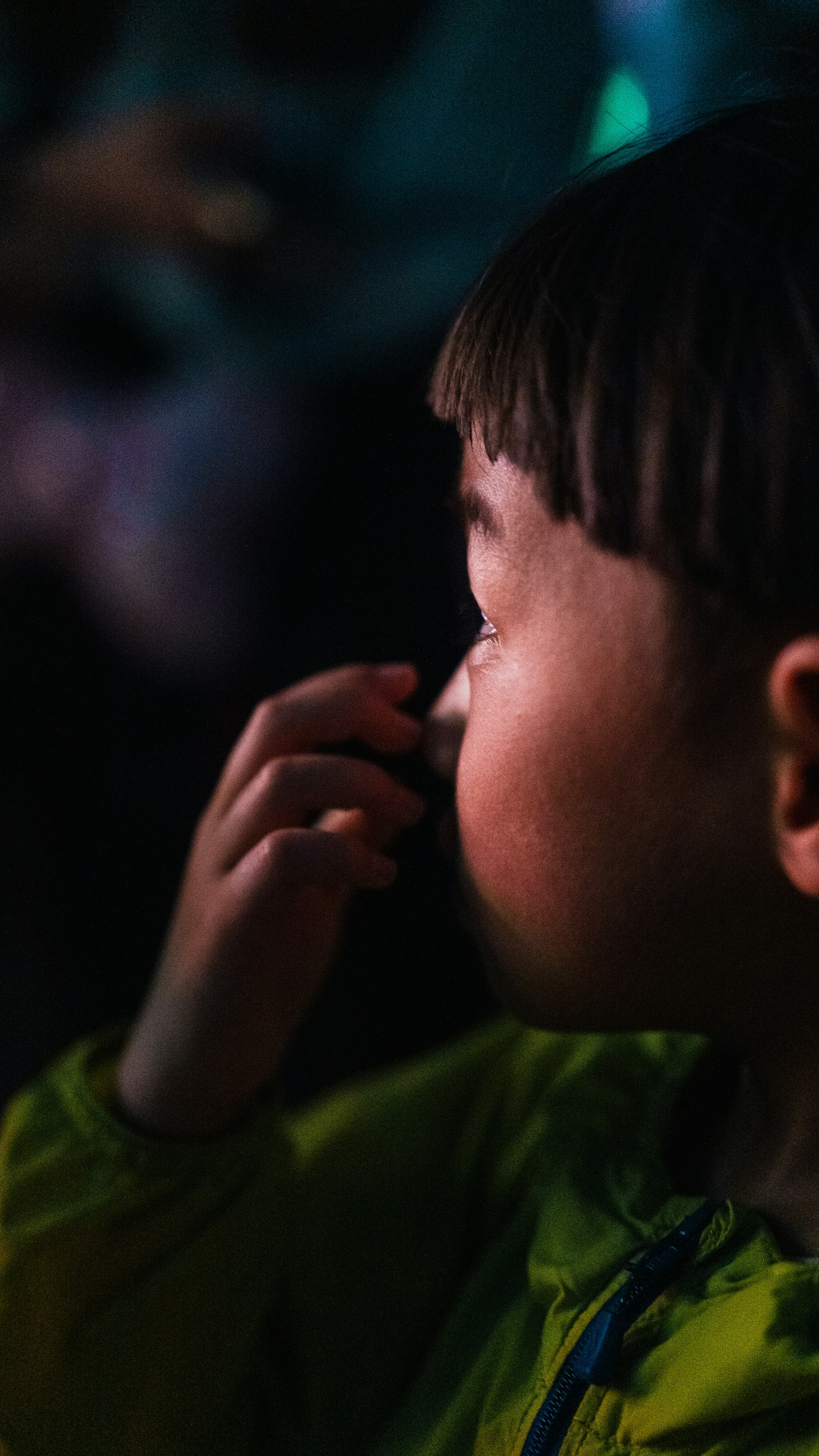 緑の服の子が手で口元に触れながら横顔で見つめる夜の雰囲気