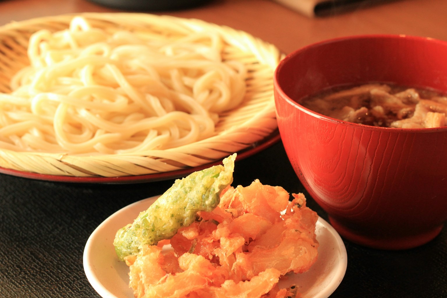 Un plato de fideos udon con tempura y salsa para mojar