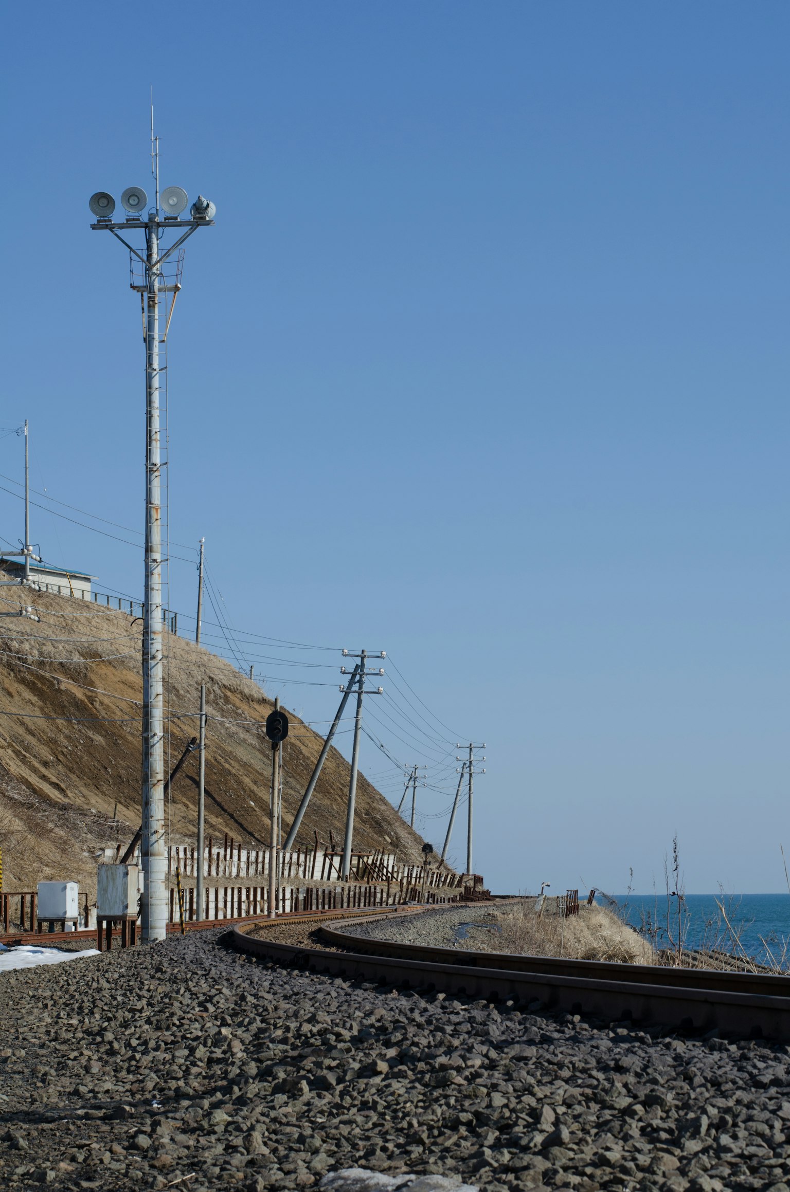 Coastal railway tracks with signal poles and blue sky