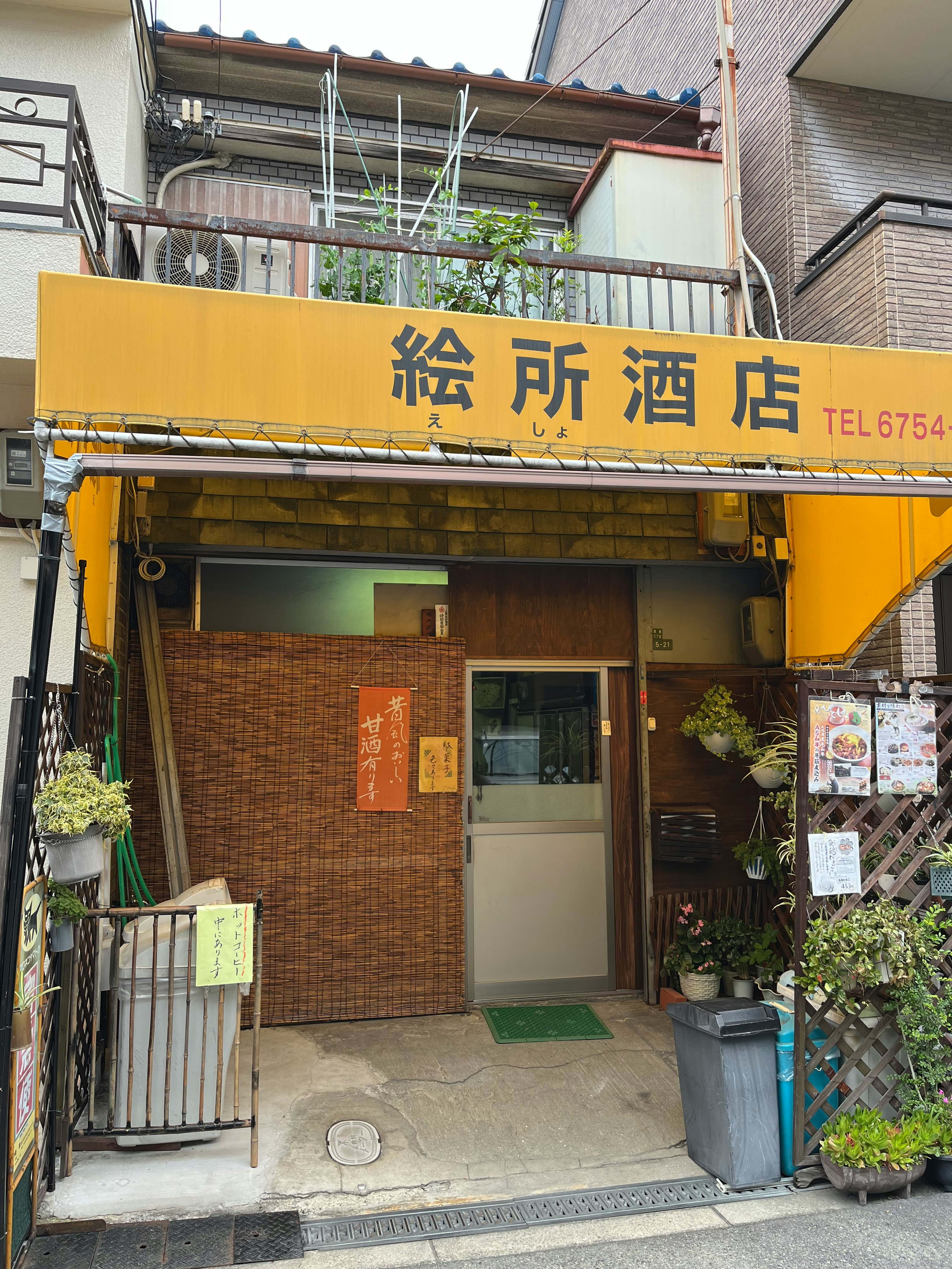 Entrance of a small liquor shop with a yellow sign