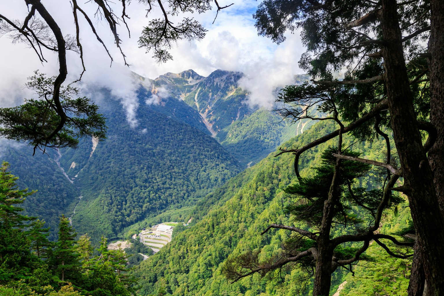 Üppiges grünes Tal umgeben von Bergen und Wolken