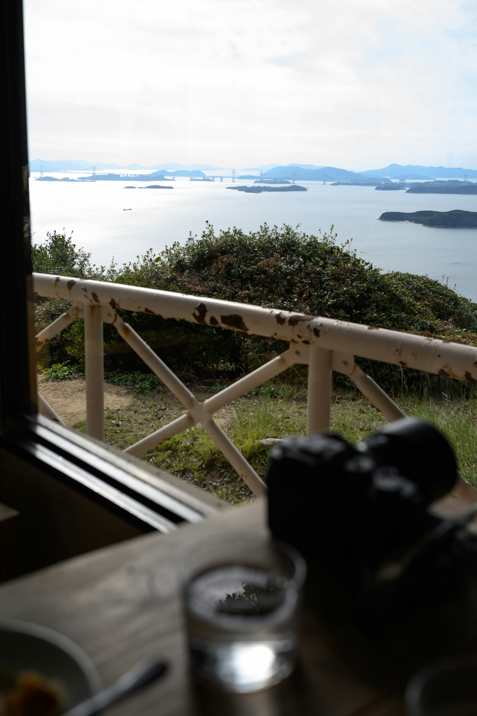 窓から見える海の景色と島々の風景 食事とカメラがテーブルに置かれている