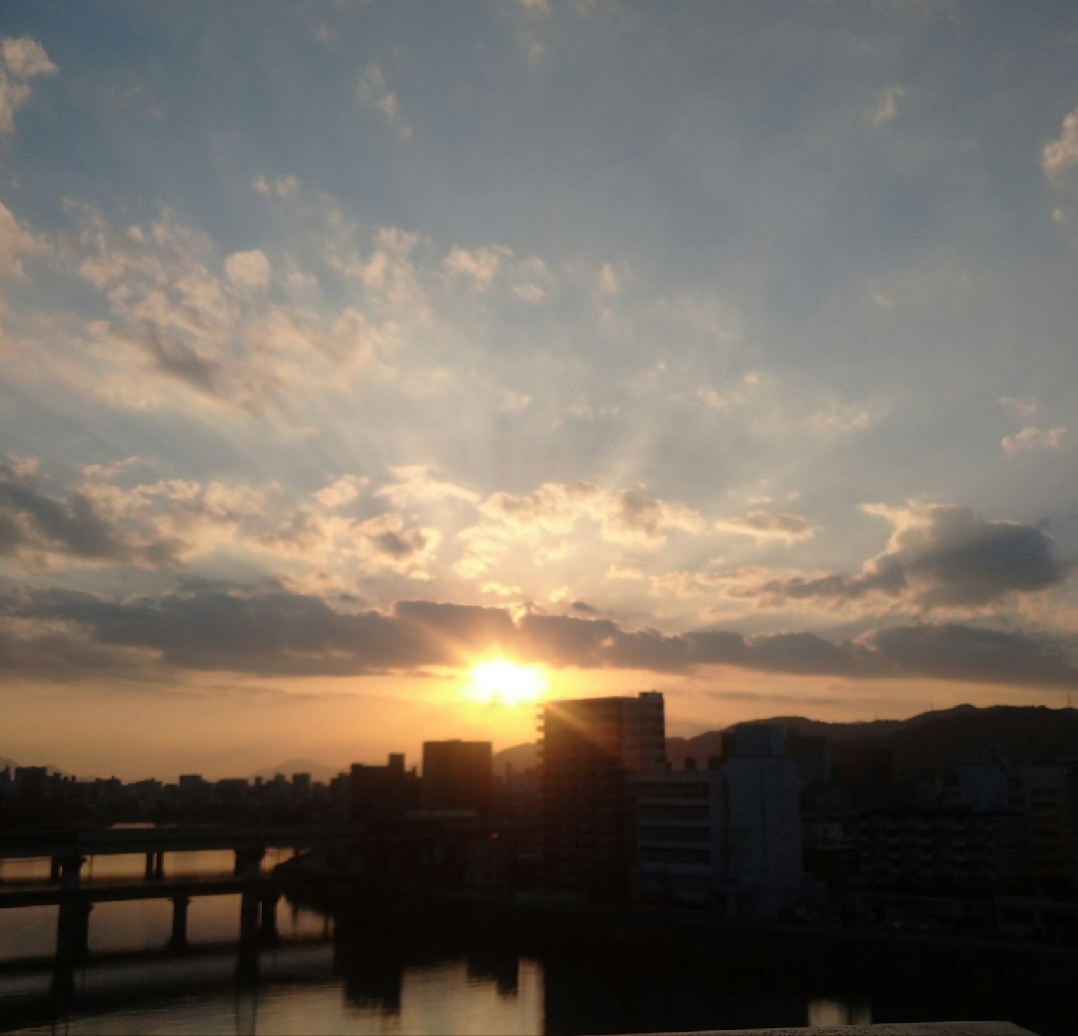 夕日が沈む都市の風景 橋と建物が映る水面