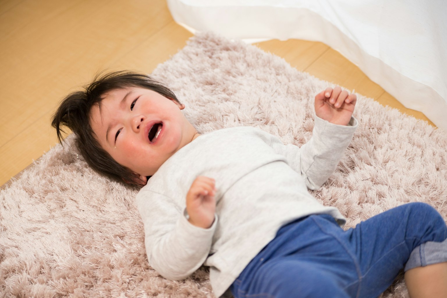 Đứa trẻ khóc nằm trên thảm mềm