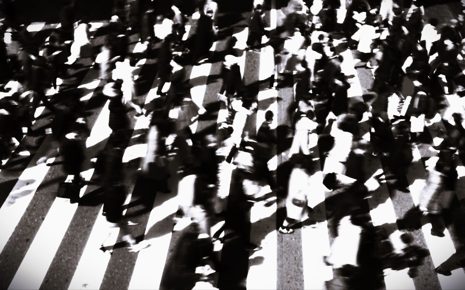 Una multitud de personas cruzando un paso peatonal en blanco y negro