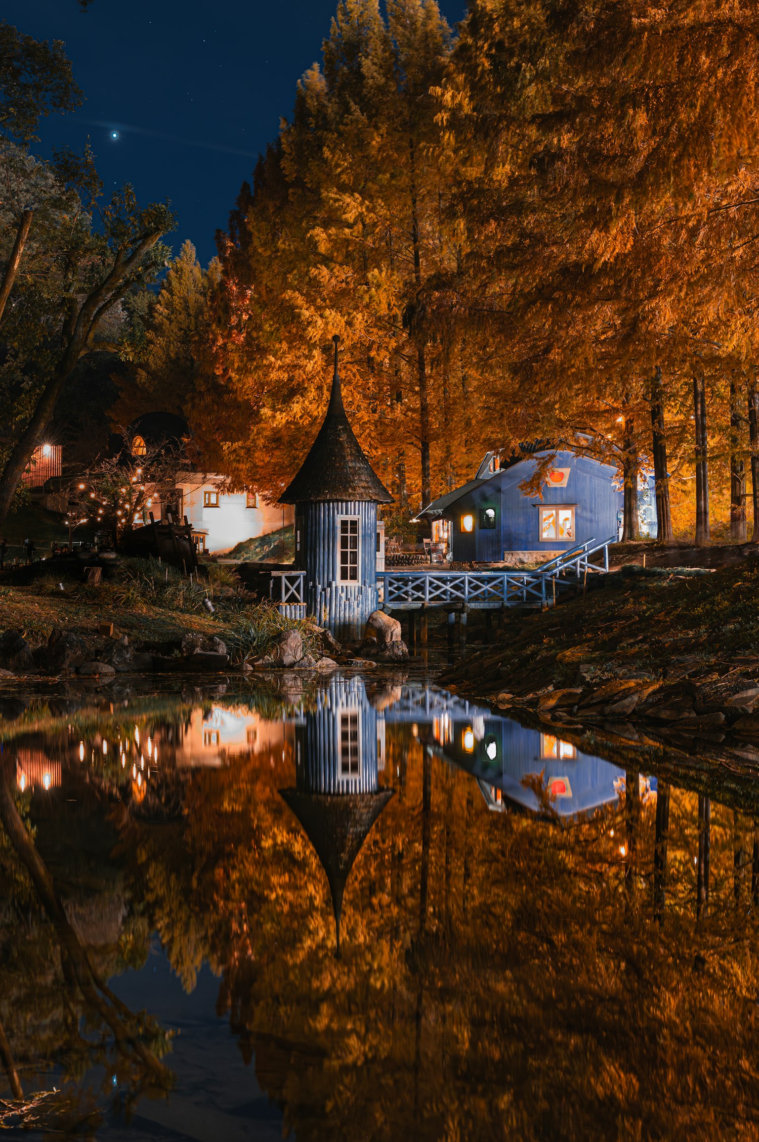 Charmante cabane et arbres se reflétant dans l'eau lors d'une nuit d'automne