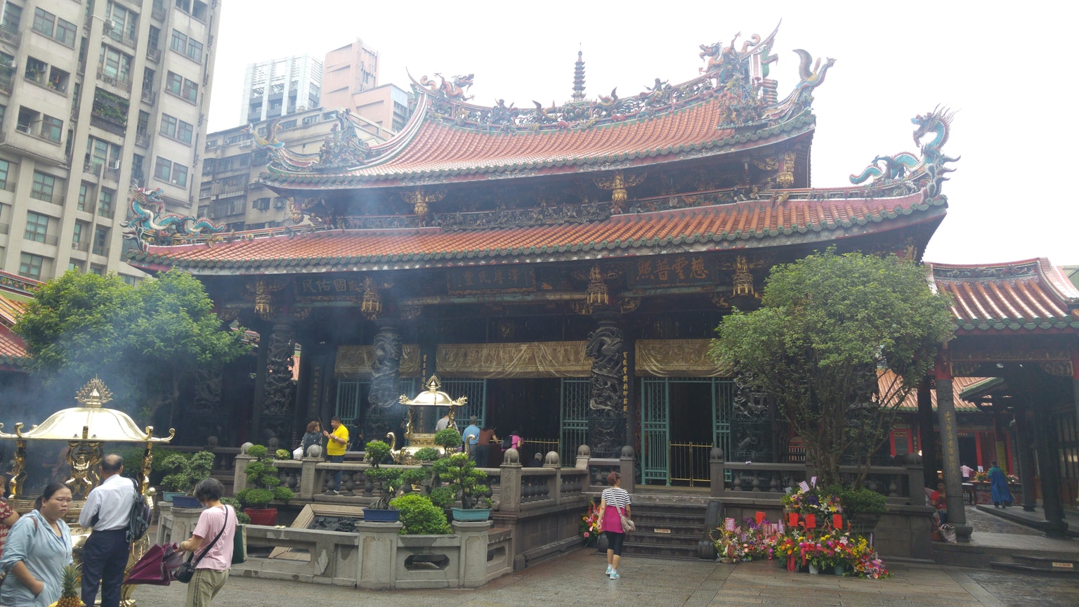 Temple traditionnel avec toit orné et visiteurs environnants