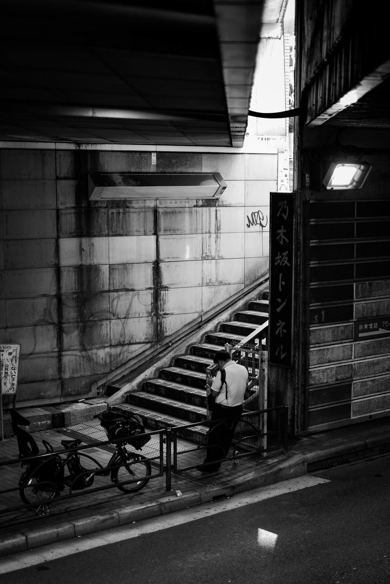 Foto en blanco y negro de un callejón oscuro con escaleras y una bicicleta