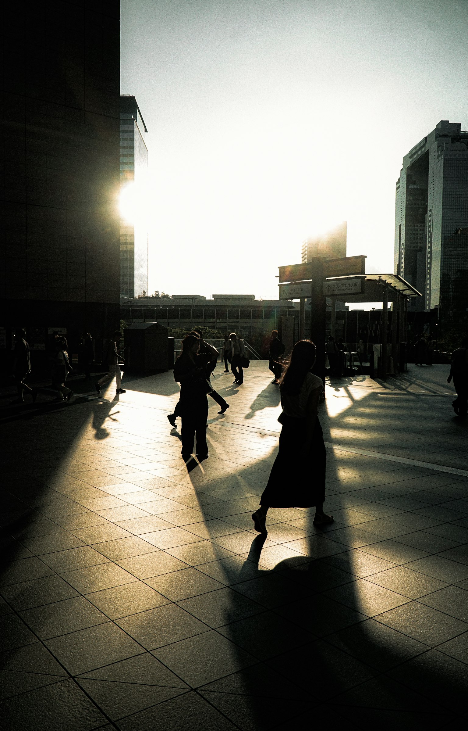 Silhouettes de personnes marchant en ville contre le coucher de soleil