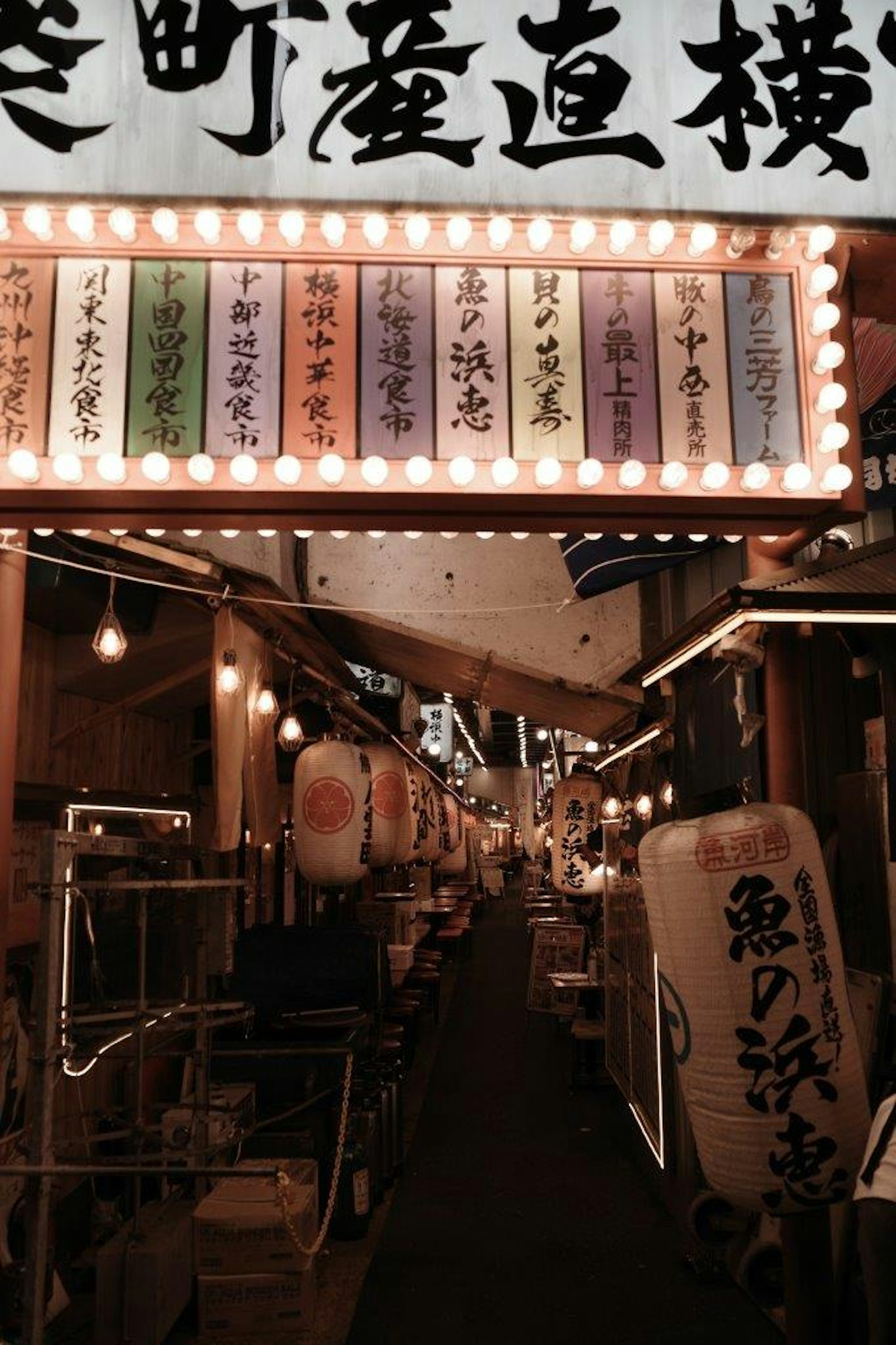 ตรอกแคบที่เต็มไปด้วยป้ายร้านอาหารที่สว่างและโคมไฟ