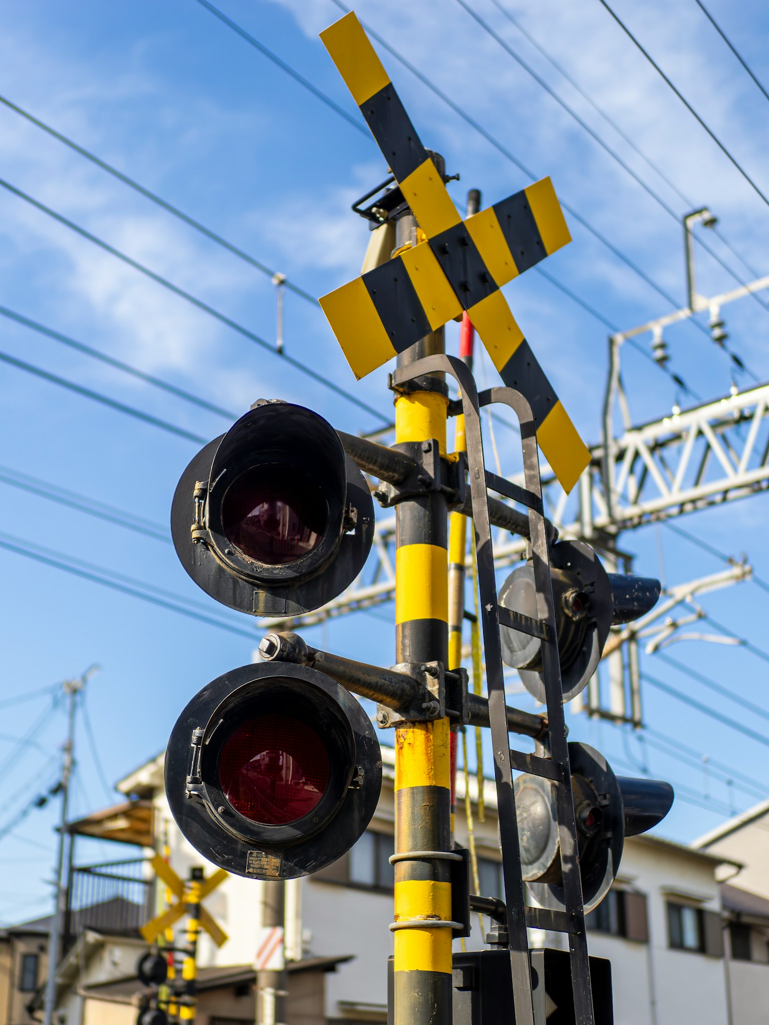 Señal ferroviaria japonesa con luces rojas y señal de advertencia