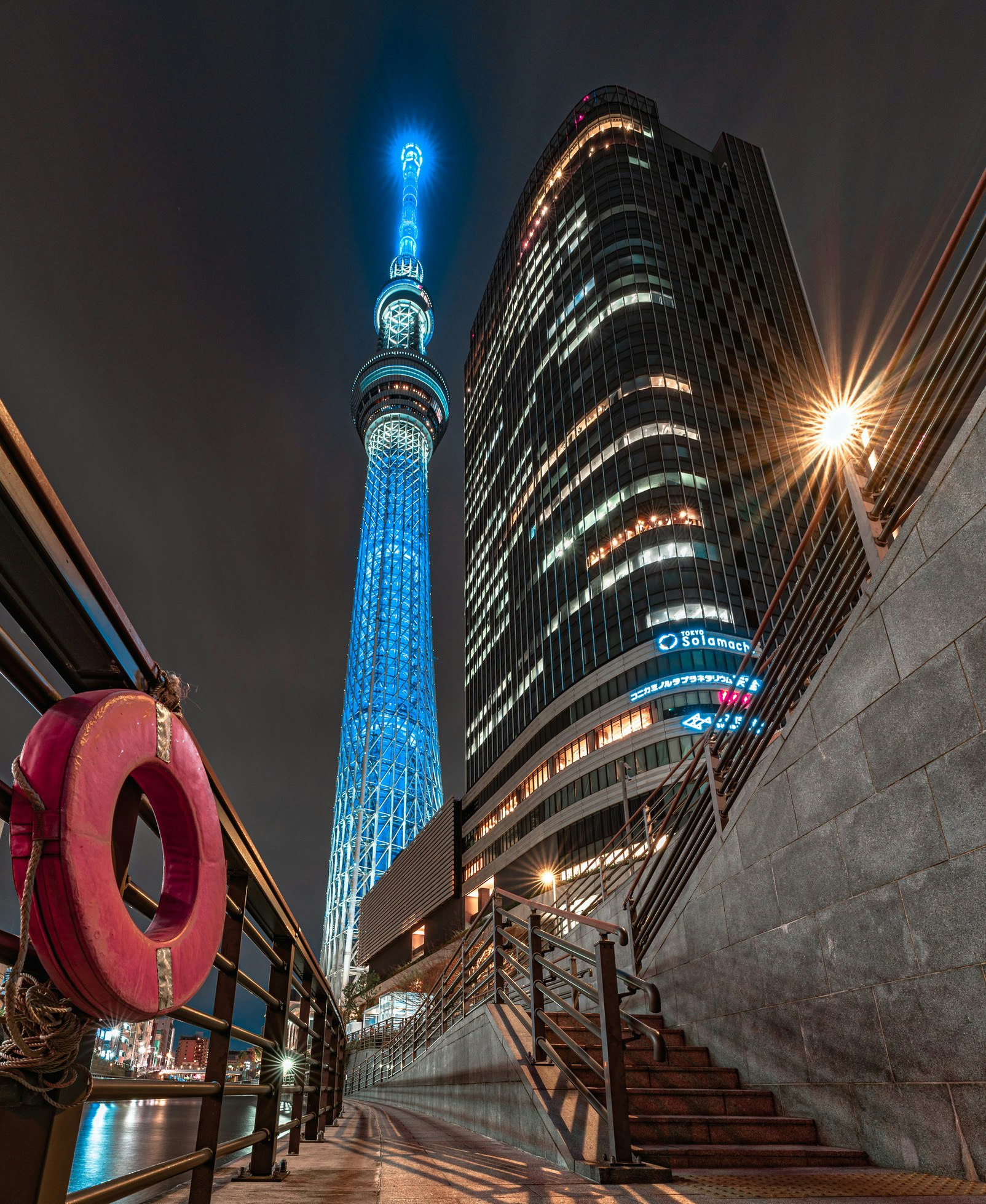Tokyo Skytree and a night skyline of high-rise buildings with a stairway walkway