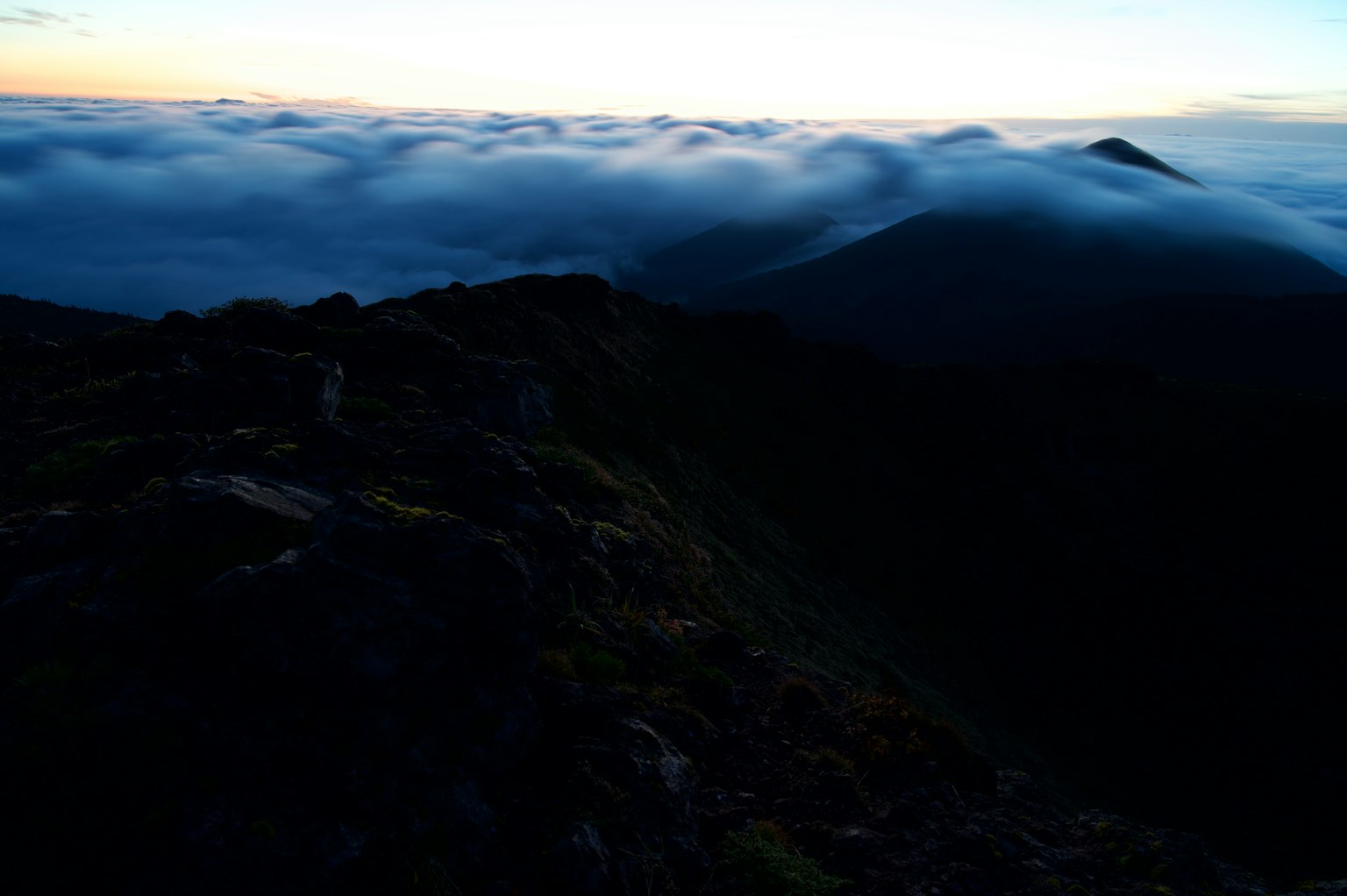 Berge über einem Wolkenmeer mit einem Dämmerungshimmel