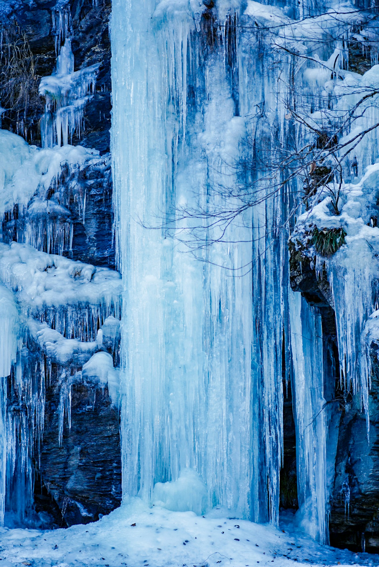 Una scena invernale con una cascata di ghiaccio e strati di ghiaccio blu