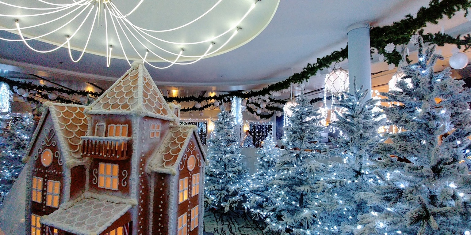 Gingerbread house in a beautifully decorated Christmas room with white Christmas trees