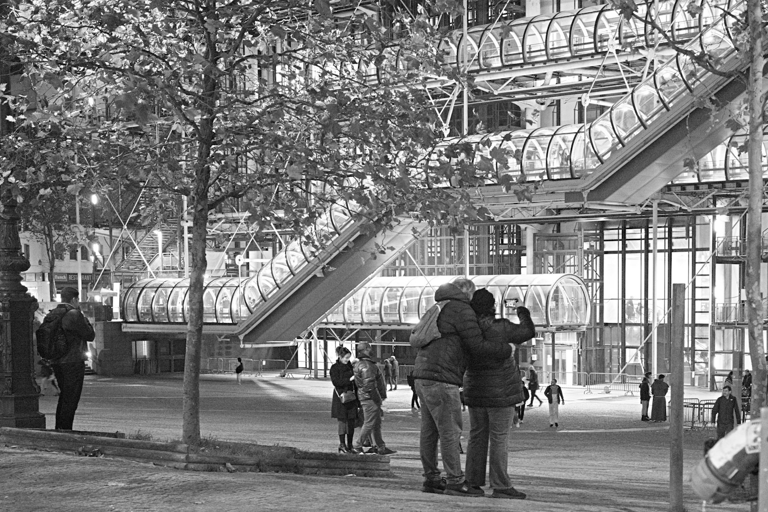 Photo en noir et blanc d'un couple s'embrassant dans un parc avec des gens autour
