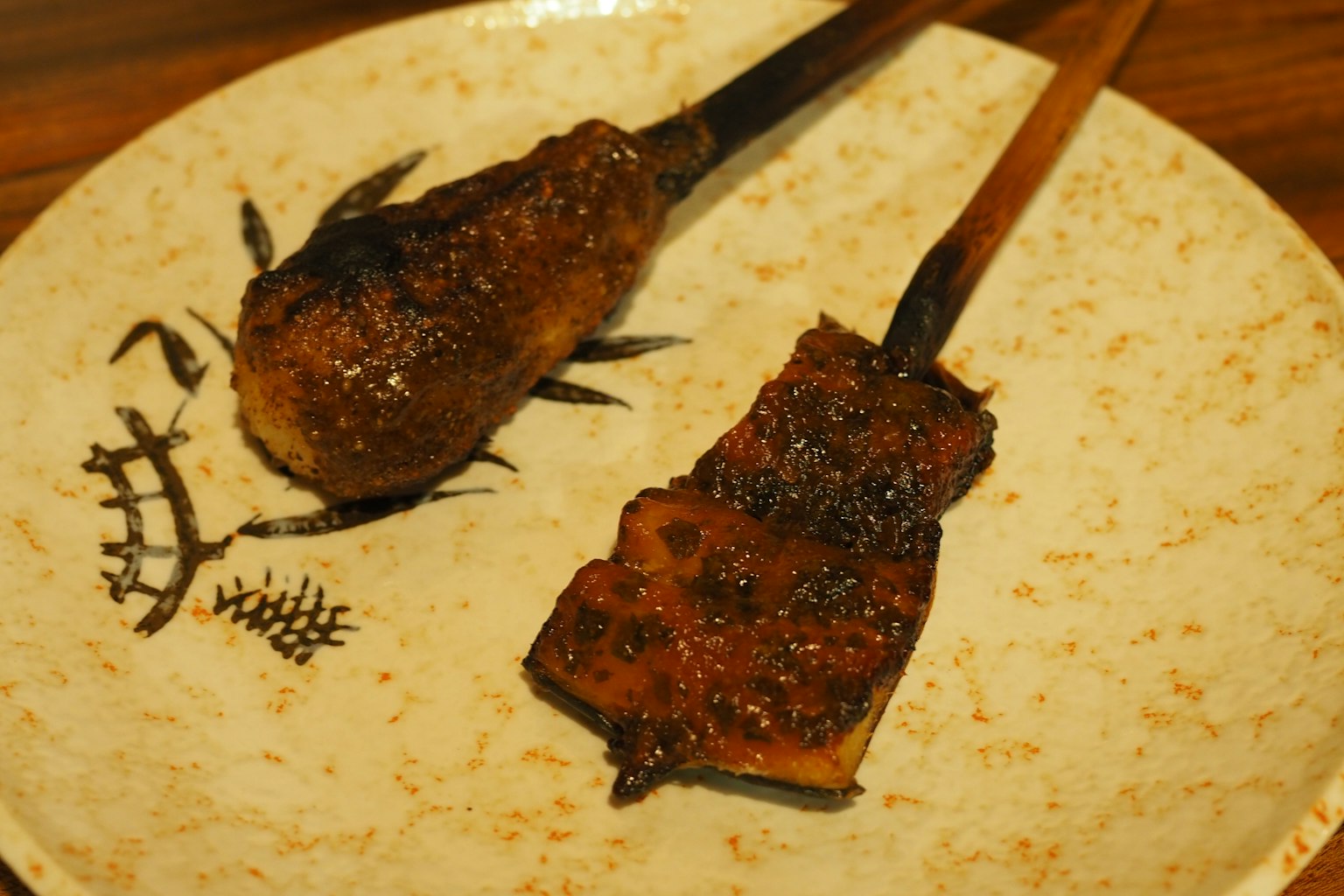 Brochettes de poulet et d'anguille grillées avec un glaçage brillant sur une assiette décorative