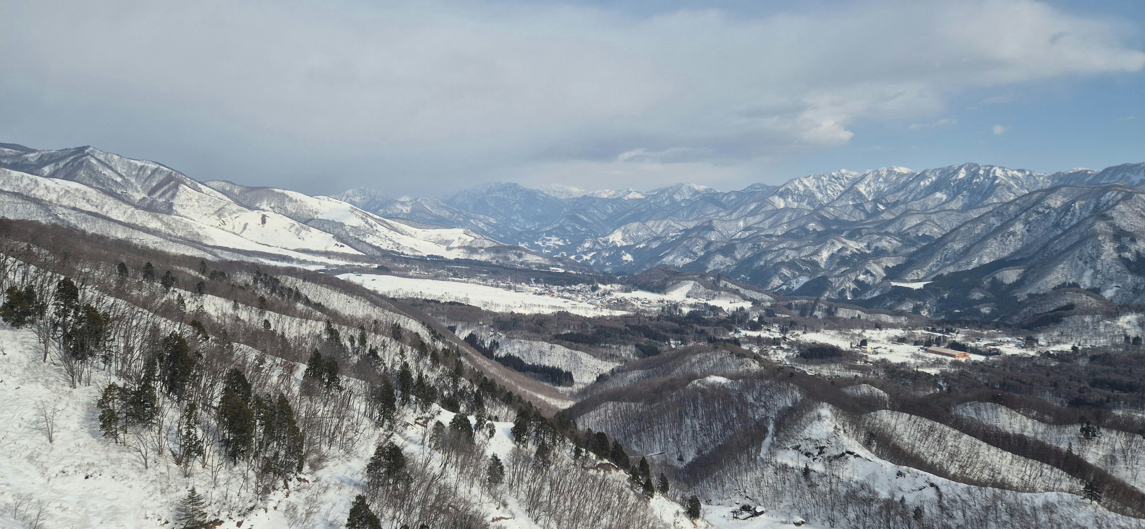 Panoramablick auf eine schneebedeckte Bergkette und ein Tal