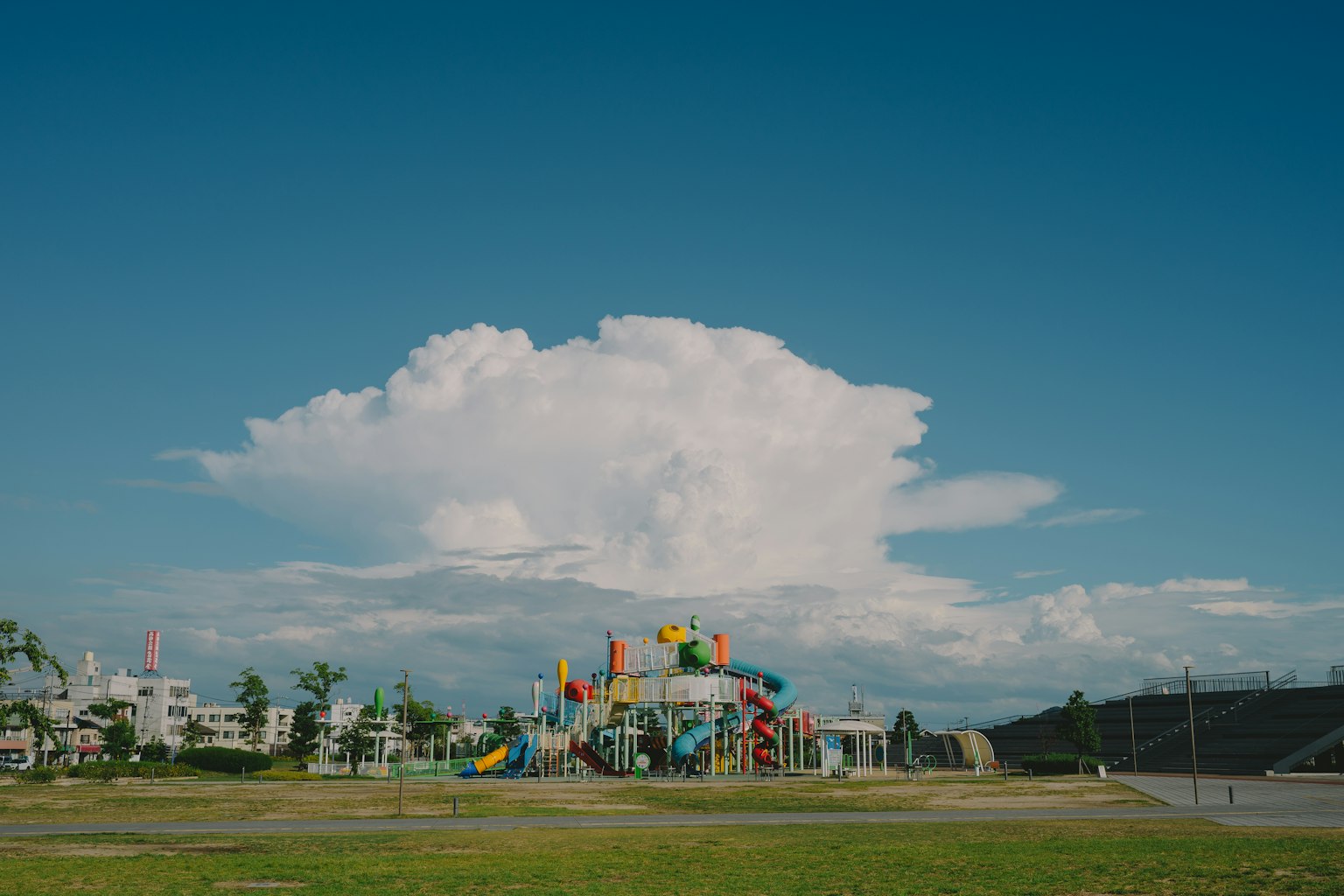 Aire de jeux colorée sous un ciel bleu avec un grand nuage
