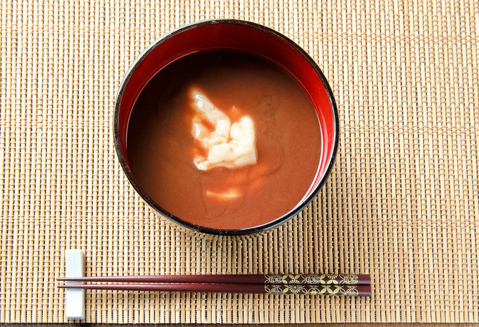 Red bowl with miso soup featuring a white tofu shape