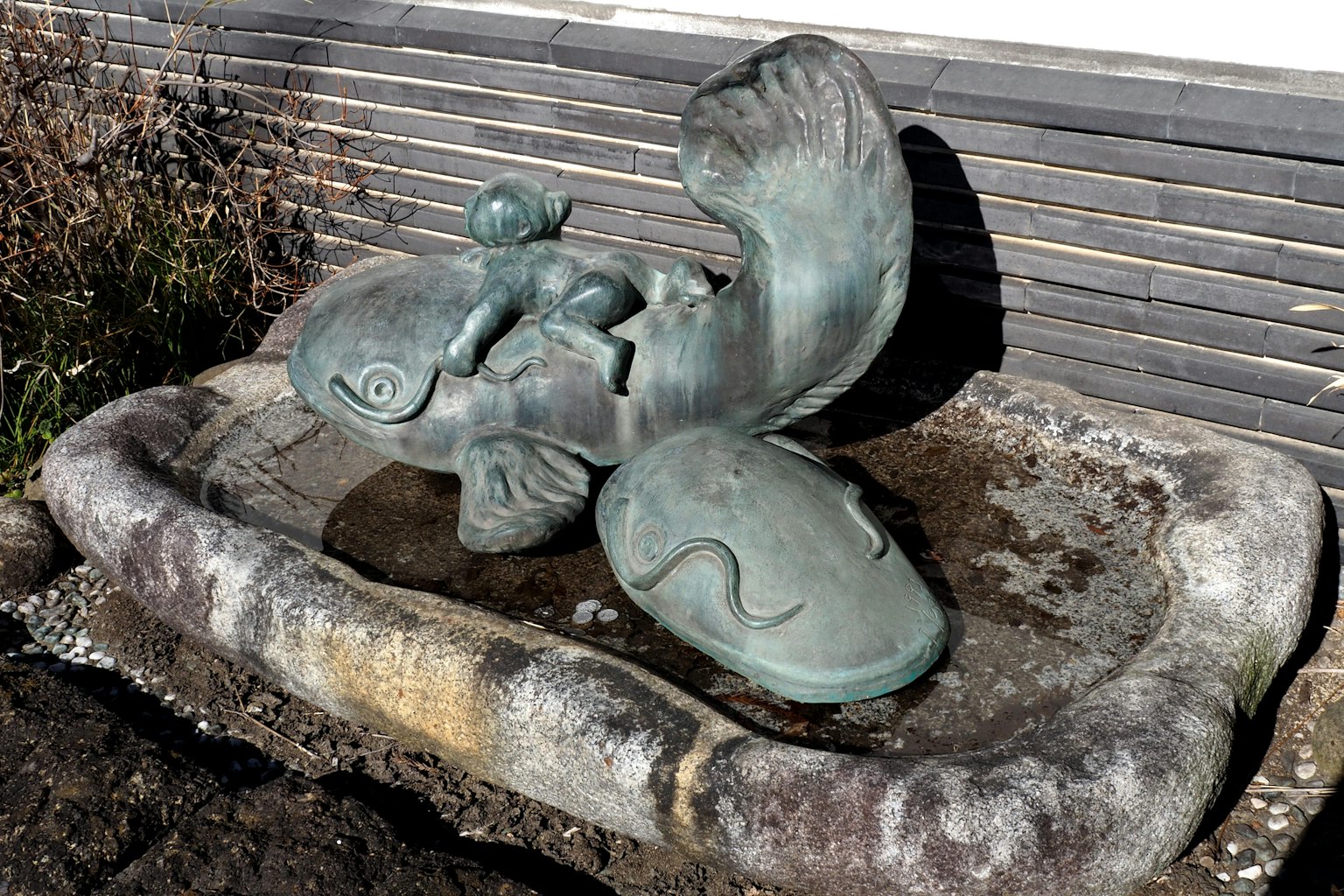 Bronze sculpture of a child sitting on a fish