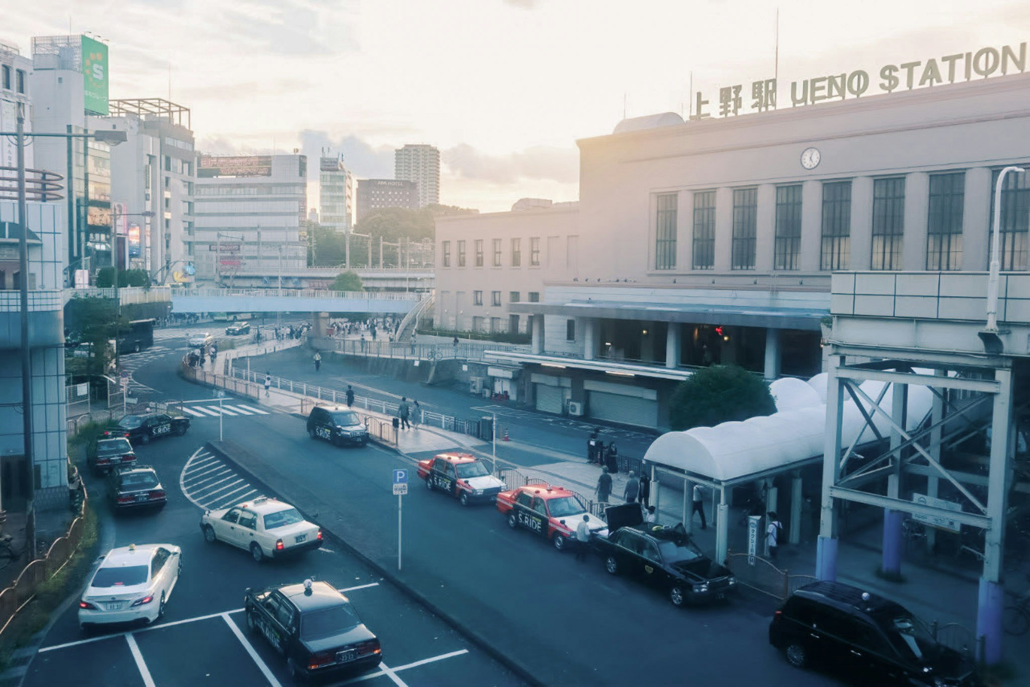 高架駅前の道路とバス・車のある都市風景