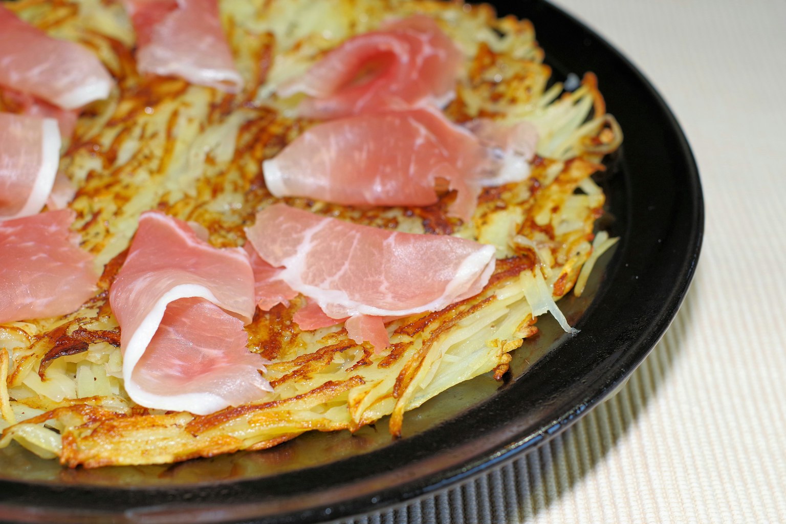 Un piatto con hash browns guarniti con fette di prosciutto