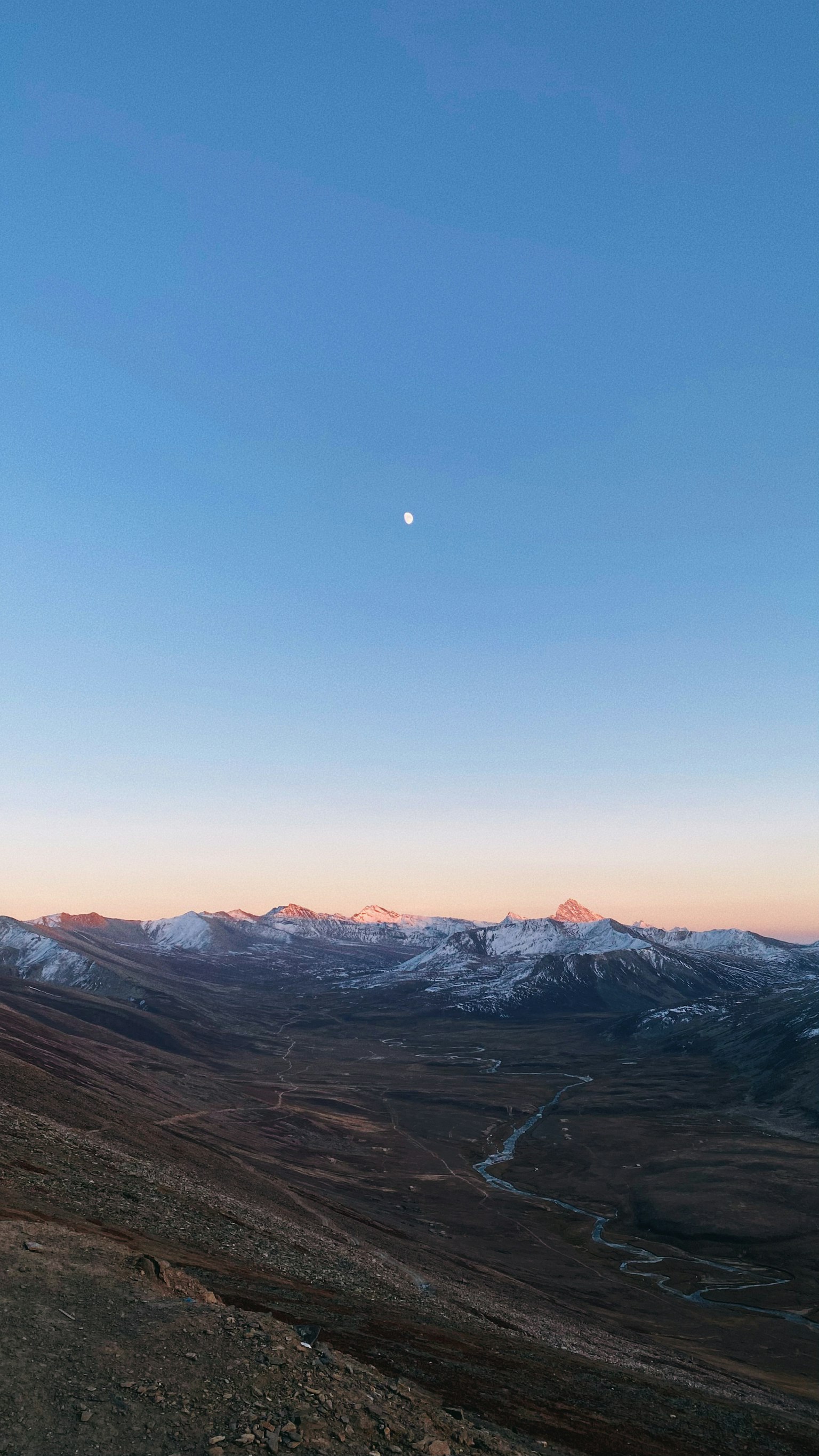 Bulan di langit biru cerah di atas gunung bersalju