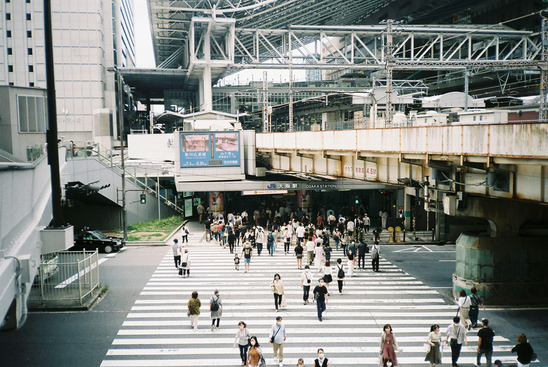 ampio passaggio della stazione con persone che camminano sotto i binari sopraelevati