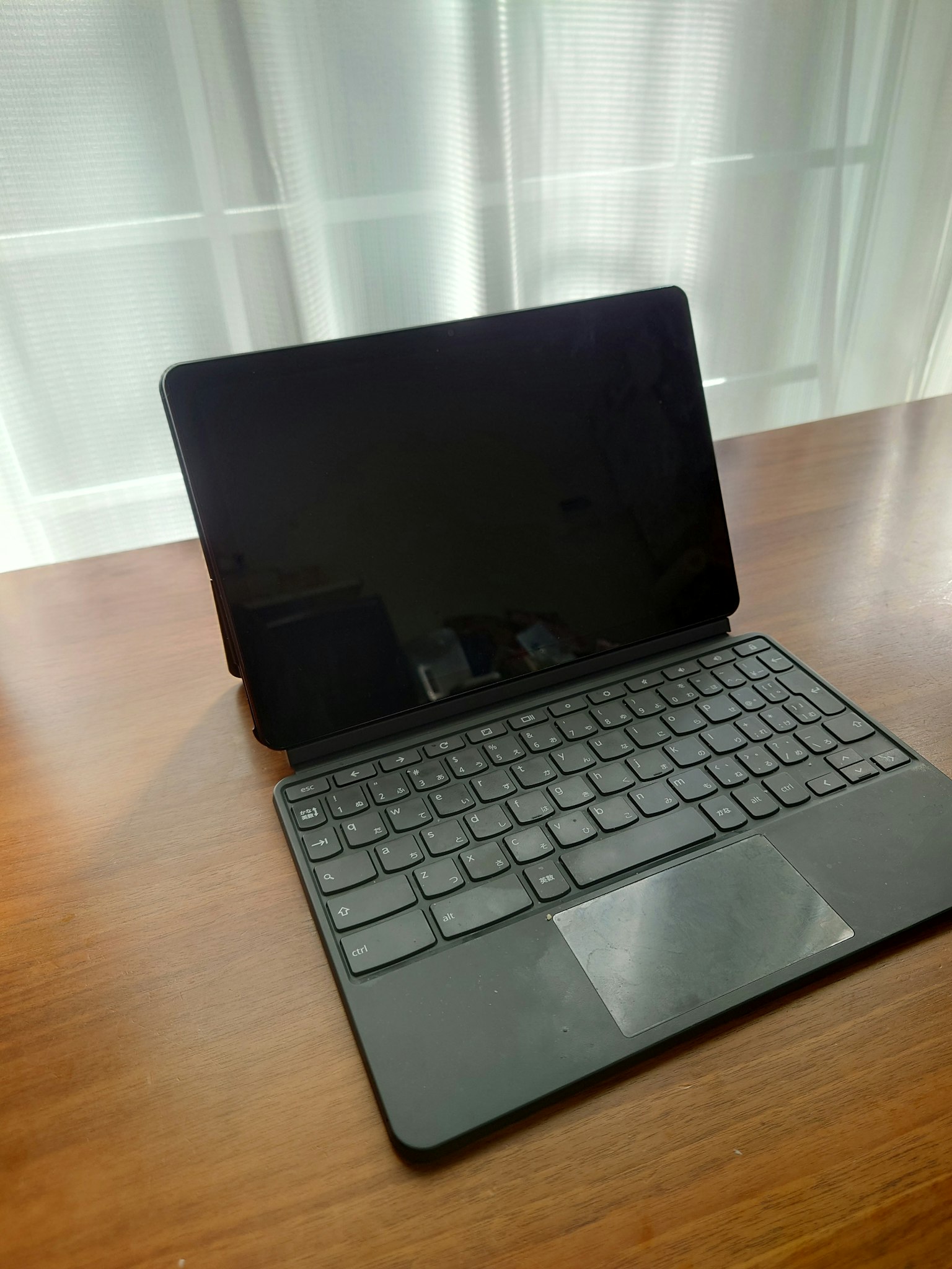 A black keyboard-equipped tablet placed on a wooden table