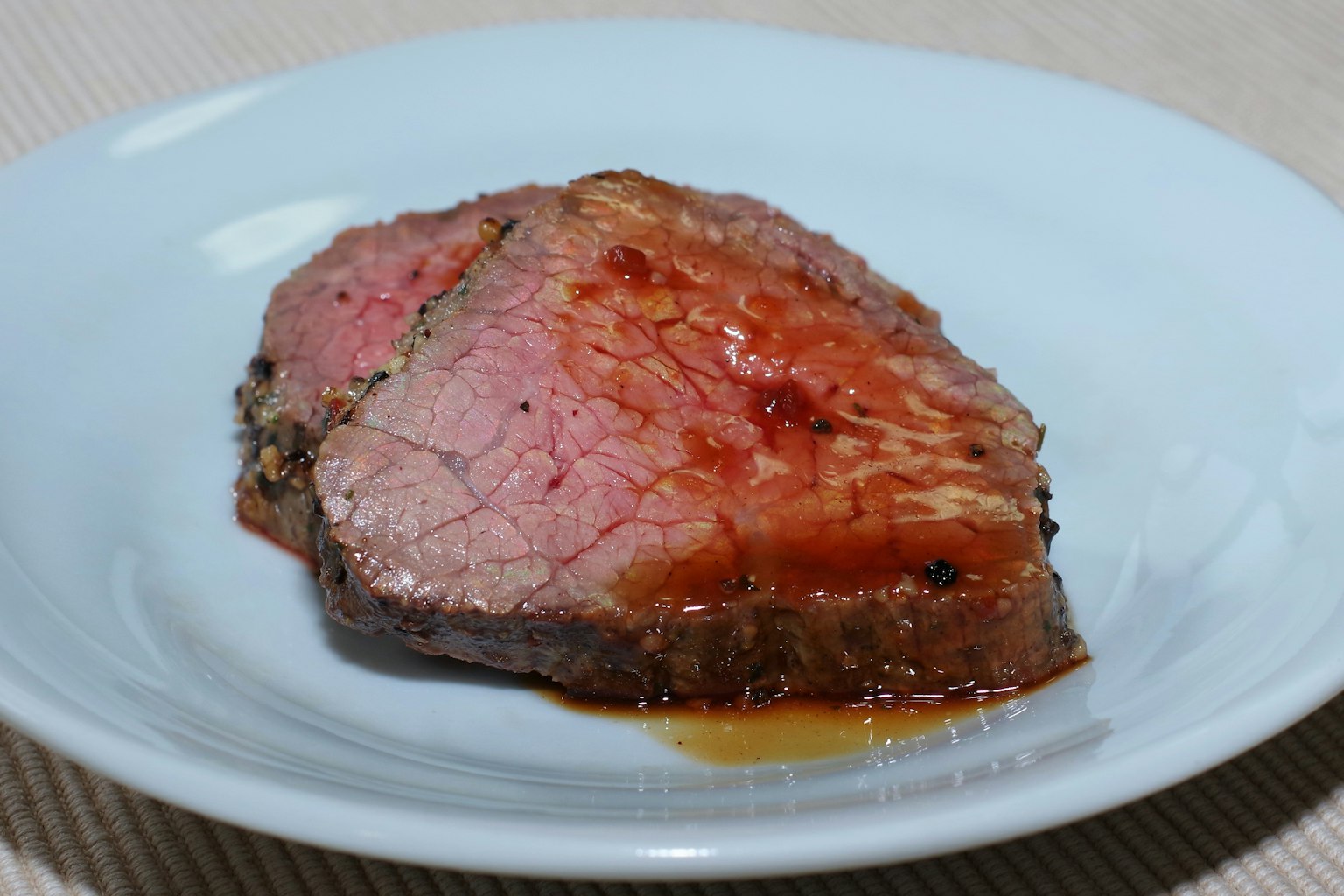 Scheibe Roastbeef mit roter Sauce auf einem weißen Teller