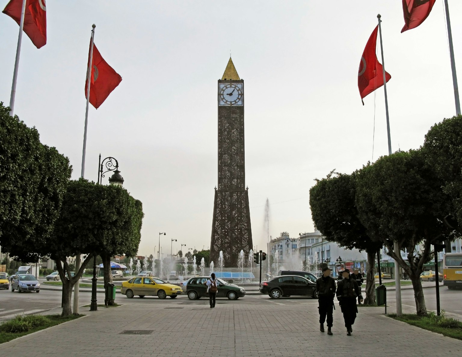 Pemandangan menara jam dengan bendera merah di alun-alun