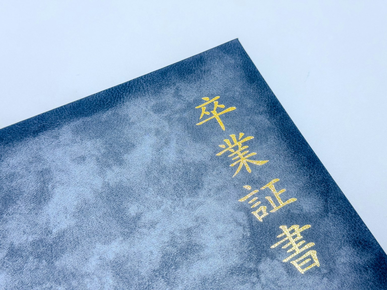 藍色畢業證書封面上有金色字母