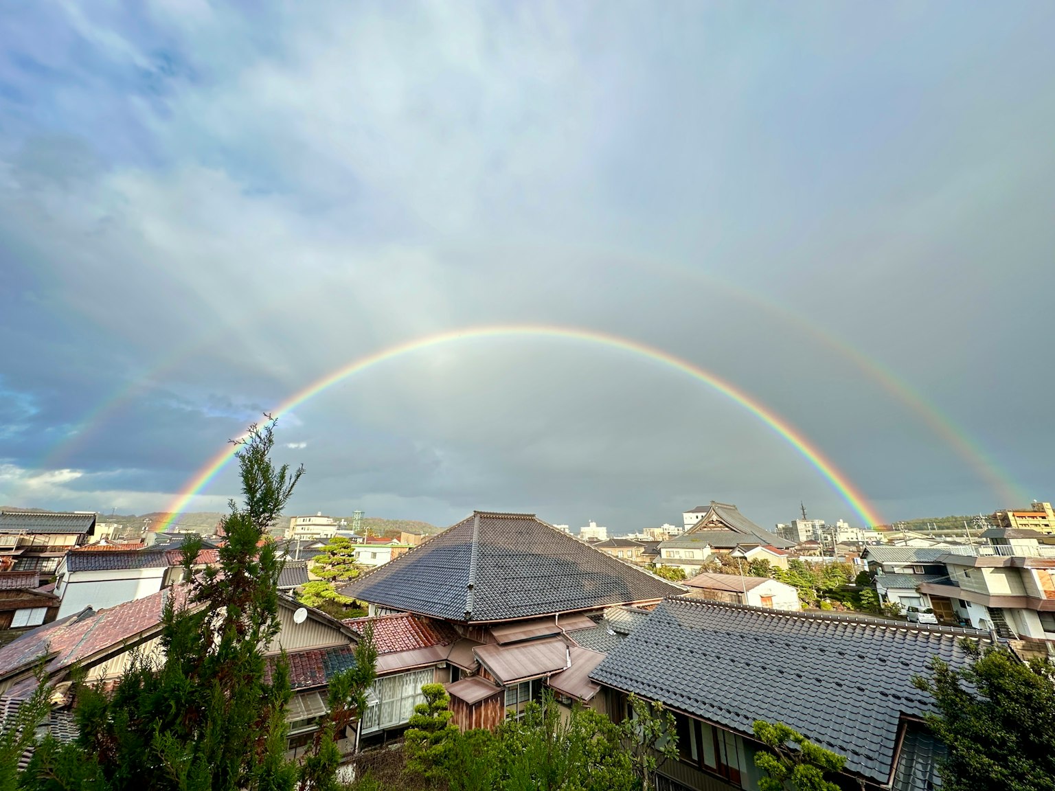 美麗的彩虹橫跨屋頂，背景是陰雲密布的天空
