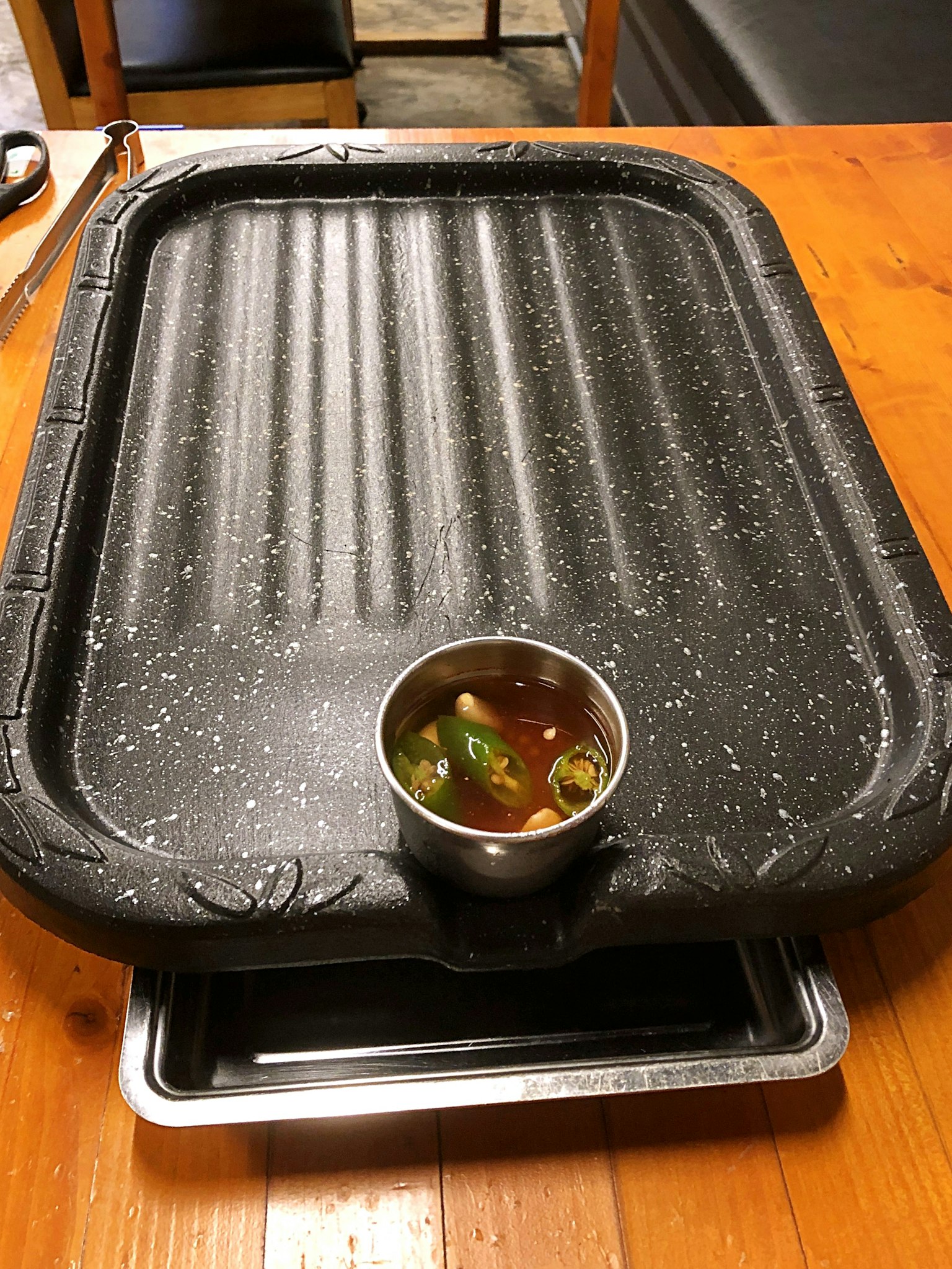 Parrilla de mesa negra con un pequeño tazón de sopa sobre una mesa de madera