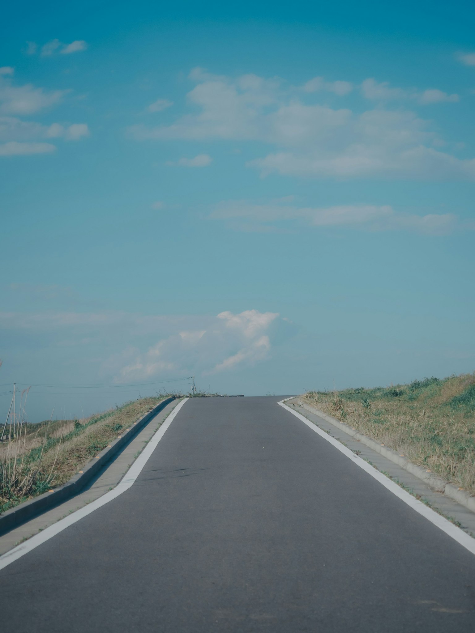 Carretera recta bajo un cielo azul con hierba verde
